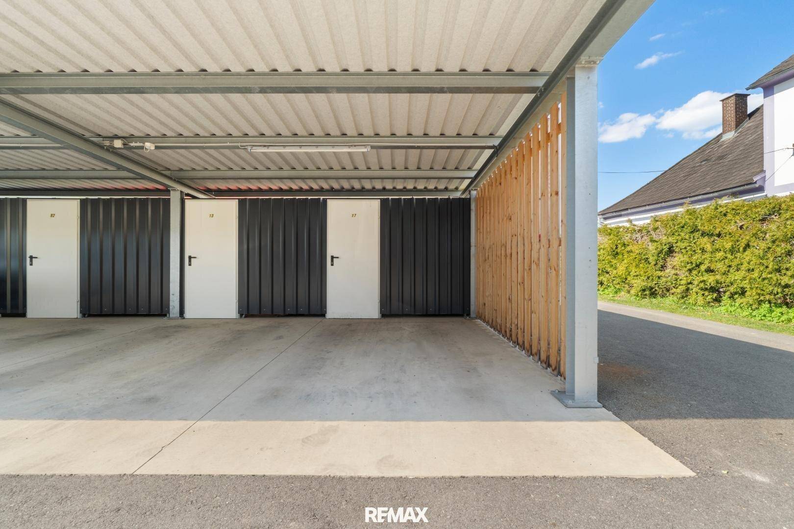 Überdachter Carport mit individuellen Abstellräumen für Bewohner.