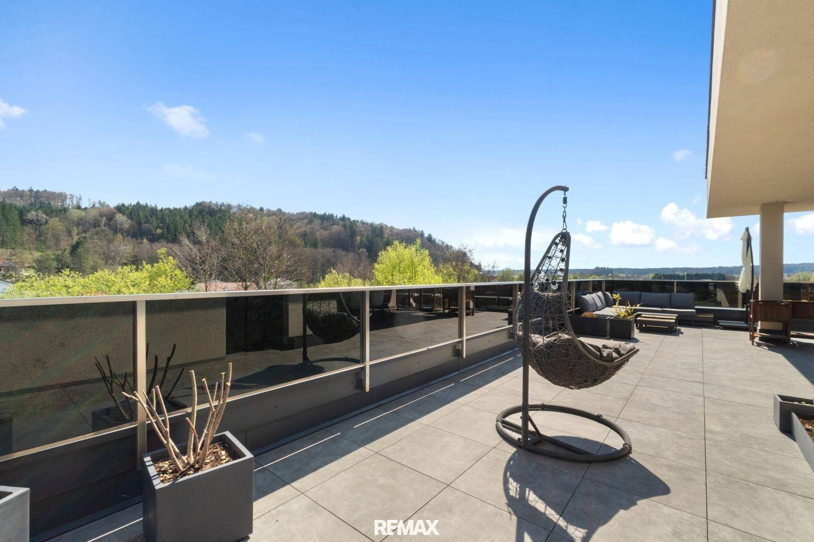 Große Dachterrasse mit Hängesessel und weitem Blick über die Landschaft.