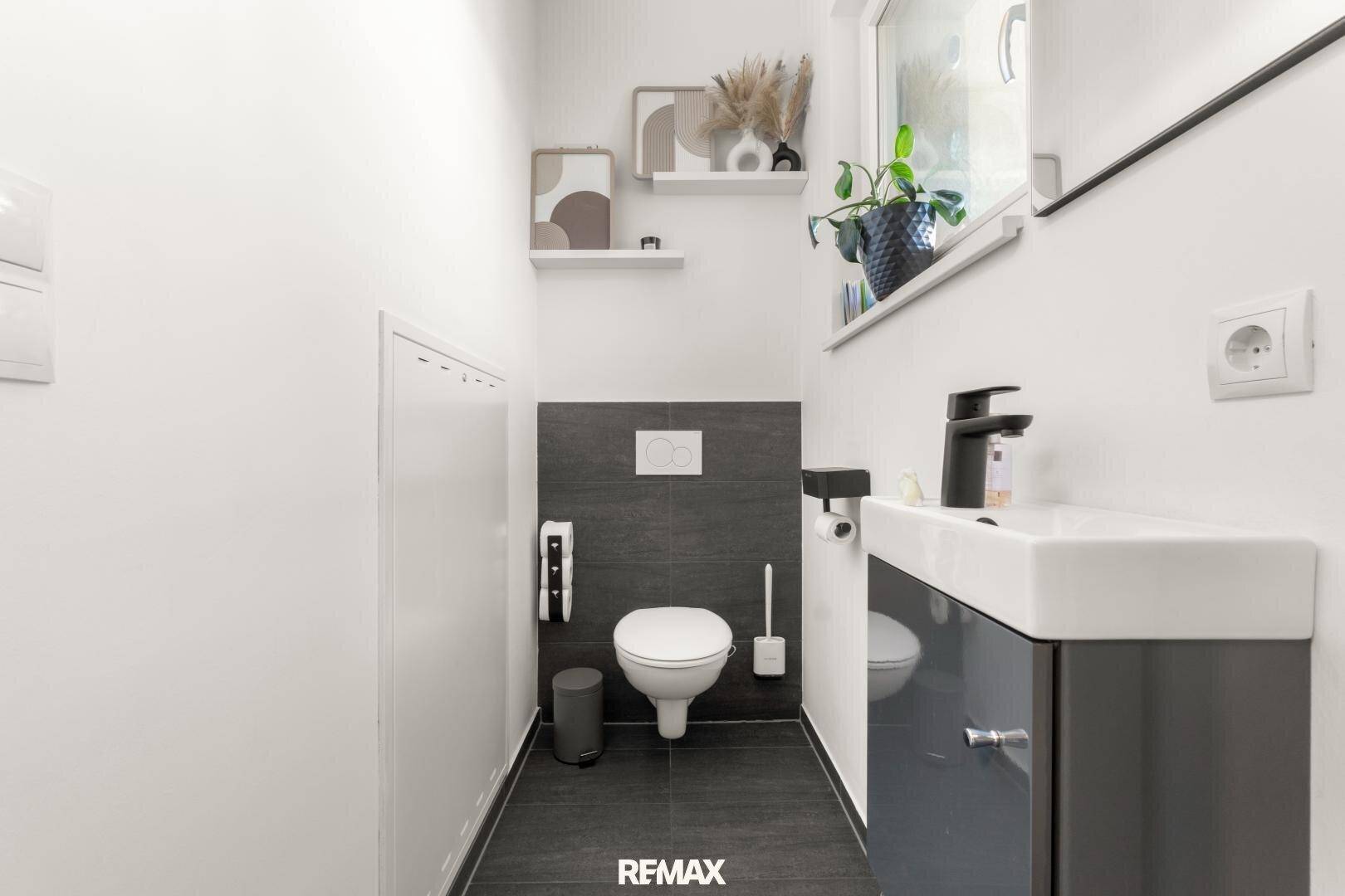 Modernes Gäste-WC mit Wand-WC, Waschbecken und Fenster.