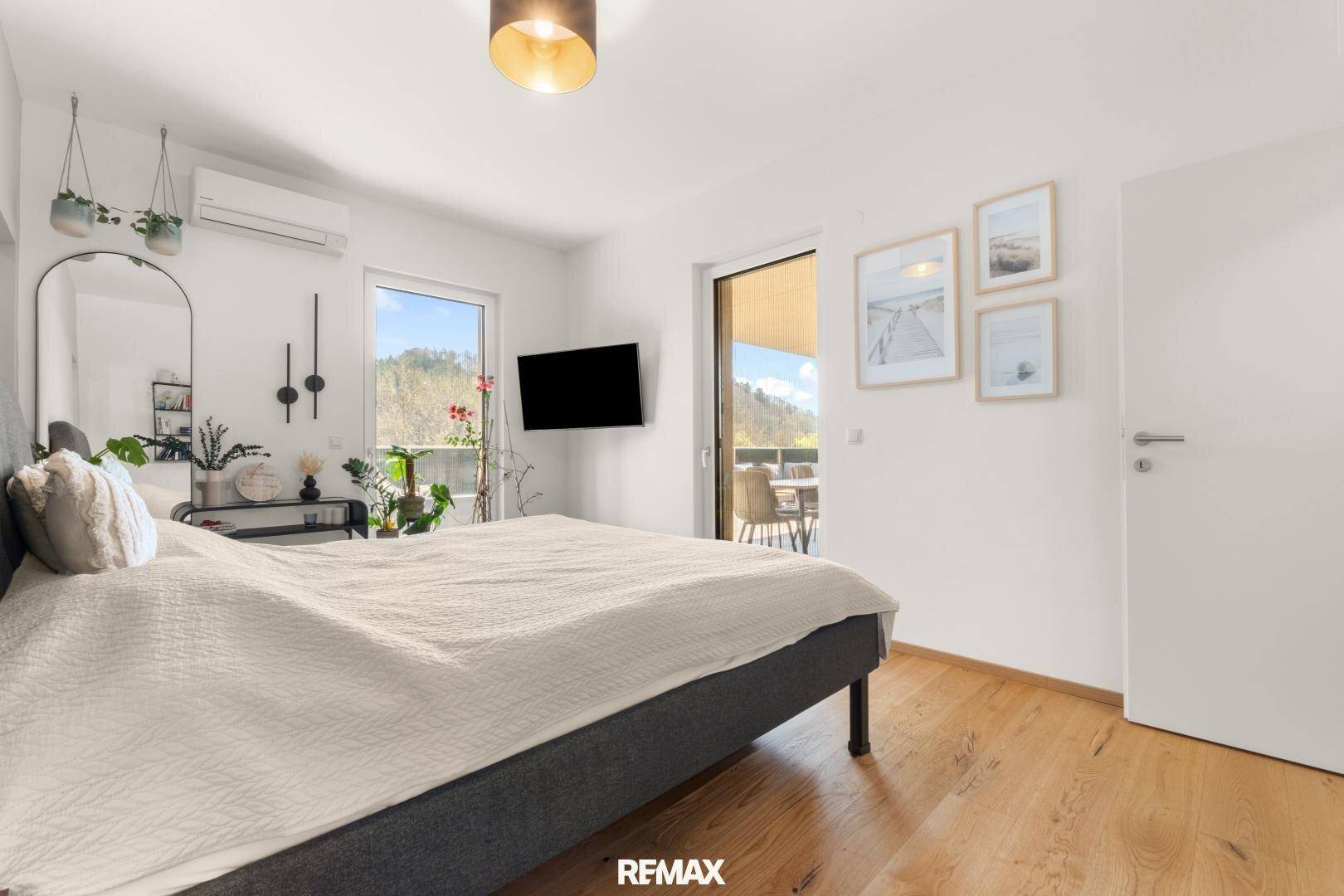 Helles Schlafzimmer mit Holzboden, Klimaanlage und Zugang zum Balkon.