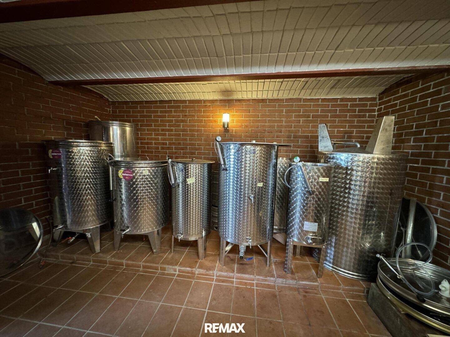 Raum im Keller mit großen Edelstahltanks für die Weinproduktion und Terrakottaboden.
