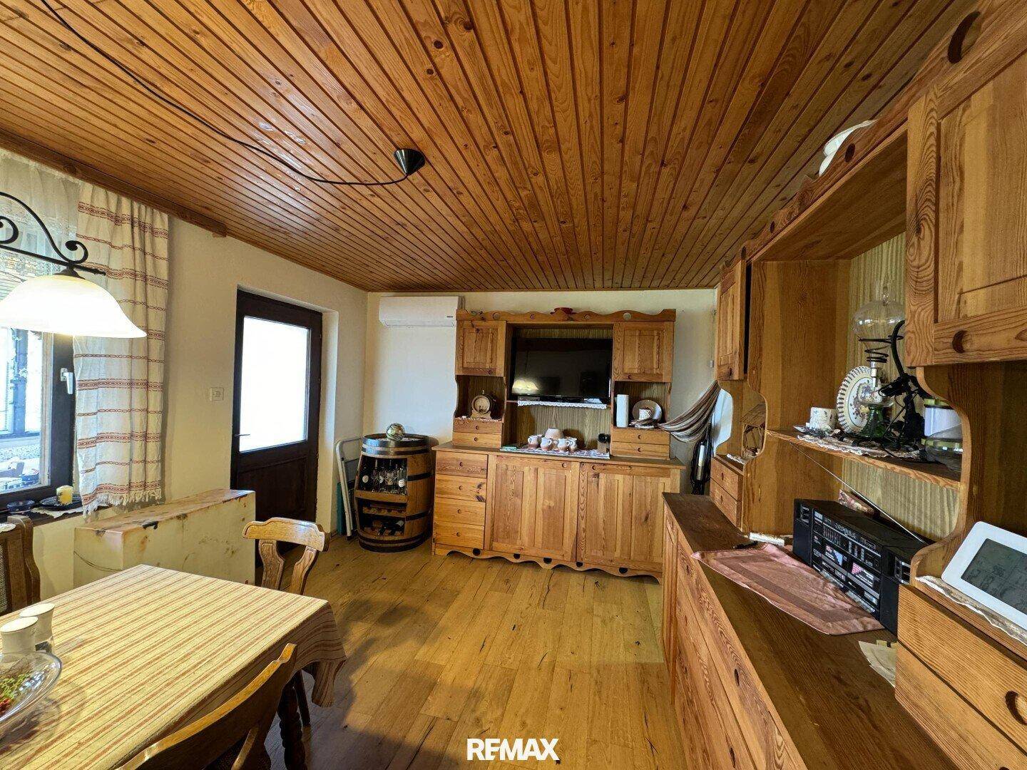 Wohnbereich mit Holzdecke, Holzboden und traditionellen Holzmöbeln, inklusive TV-Schrank.