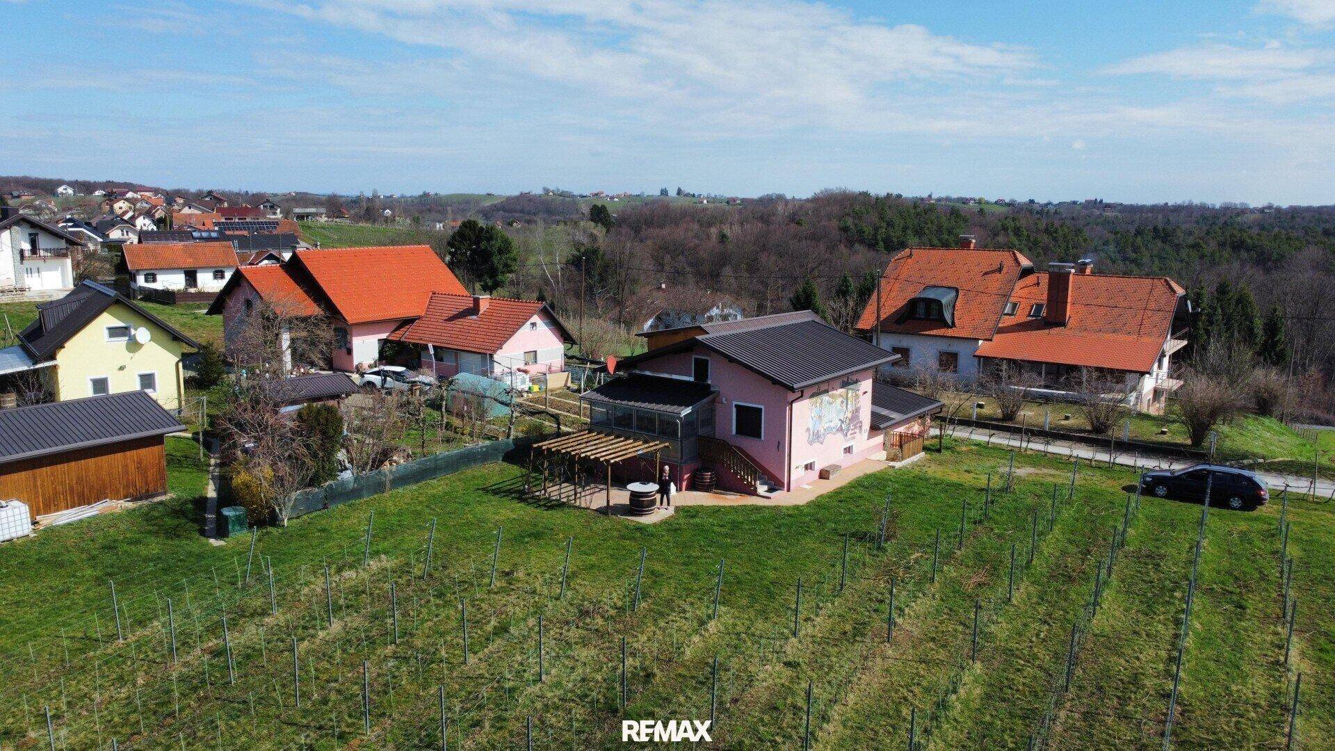 Haus mit Garten und Pergola, umgeben von Weinreben und ländlicher Landschaft.