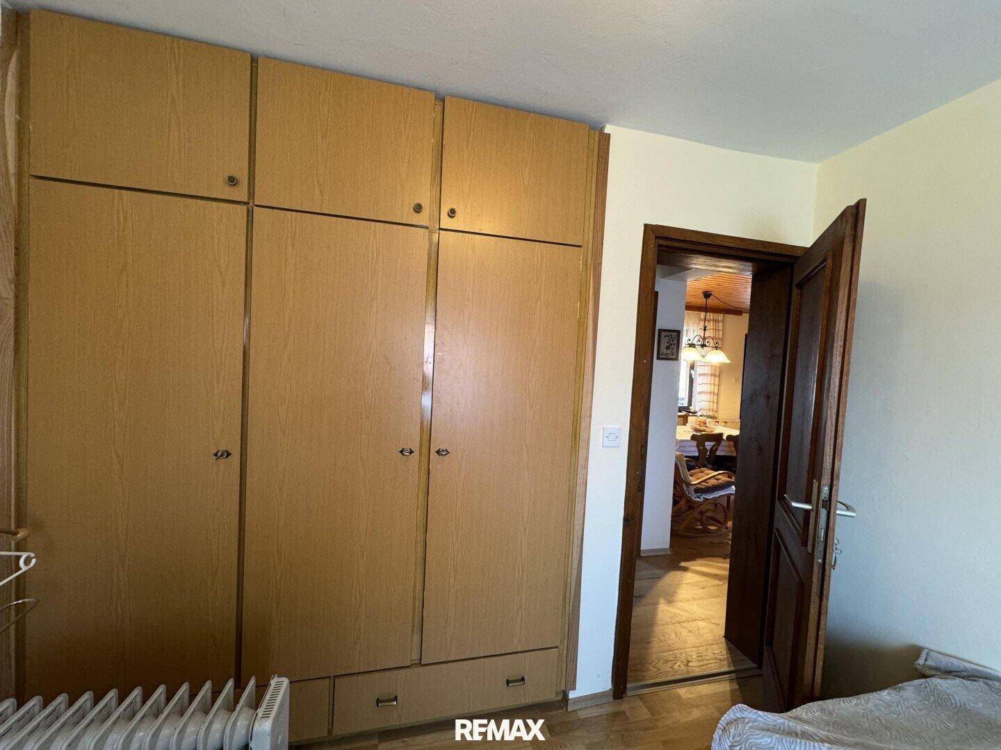 Schlafzimmer mit Einbauschränken und Holzboden, Zugang zu einem weiteren Raum.