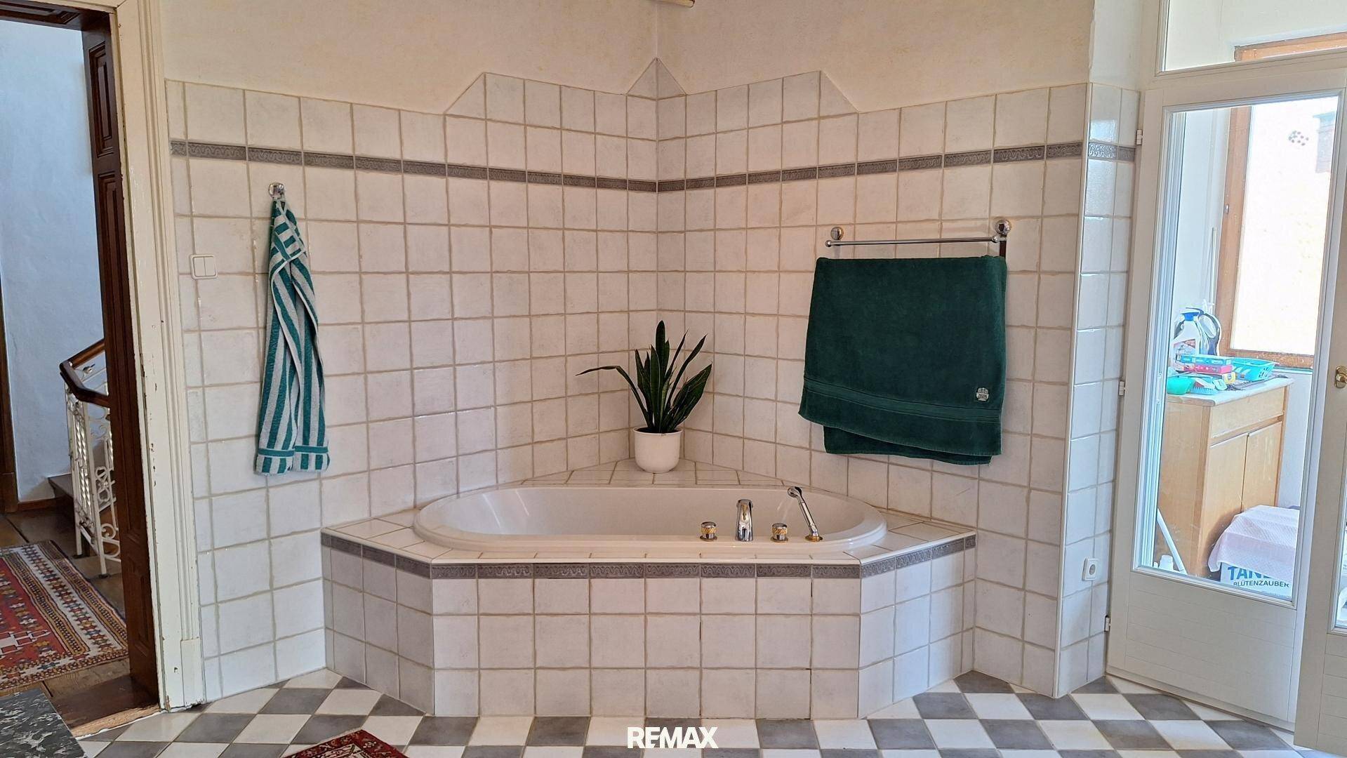 Badezimmer mit einer eingebauten Eckbadewanne und traditionellen Fliesen an Wänden und Boden.