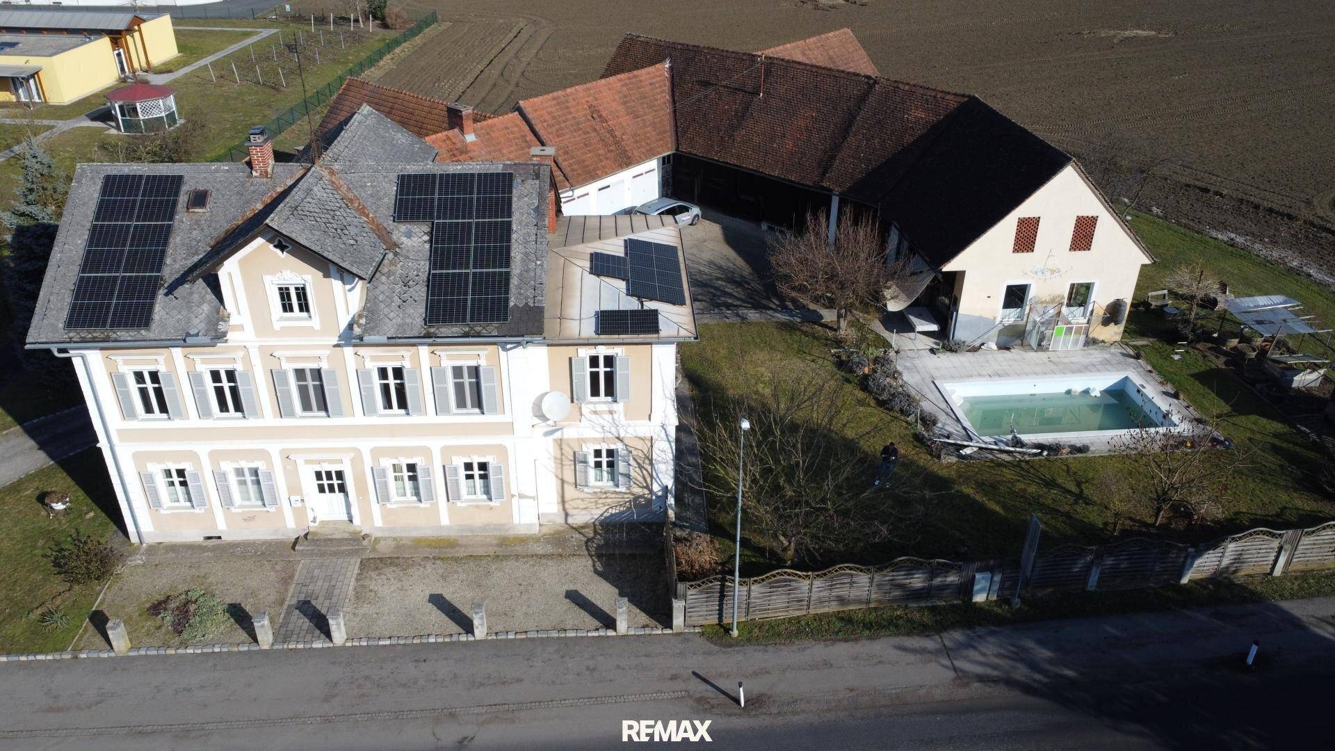 Luftaufnahme des Hauptgebäudes mit Solaranlagen auf dem Dach und der umliegenden Landschaft.