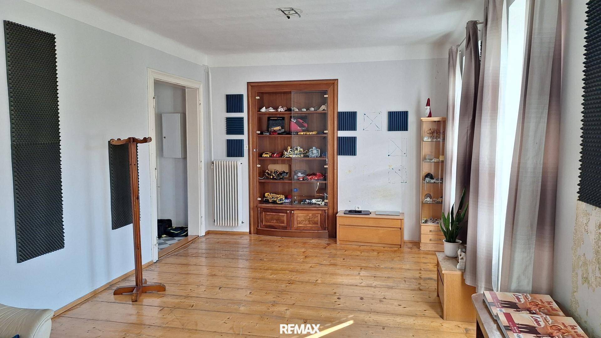Heller Raum mit Holzdielenboden, Vitrinen und schallabsorbierenden Paneelen an den Wänden.