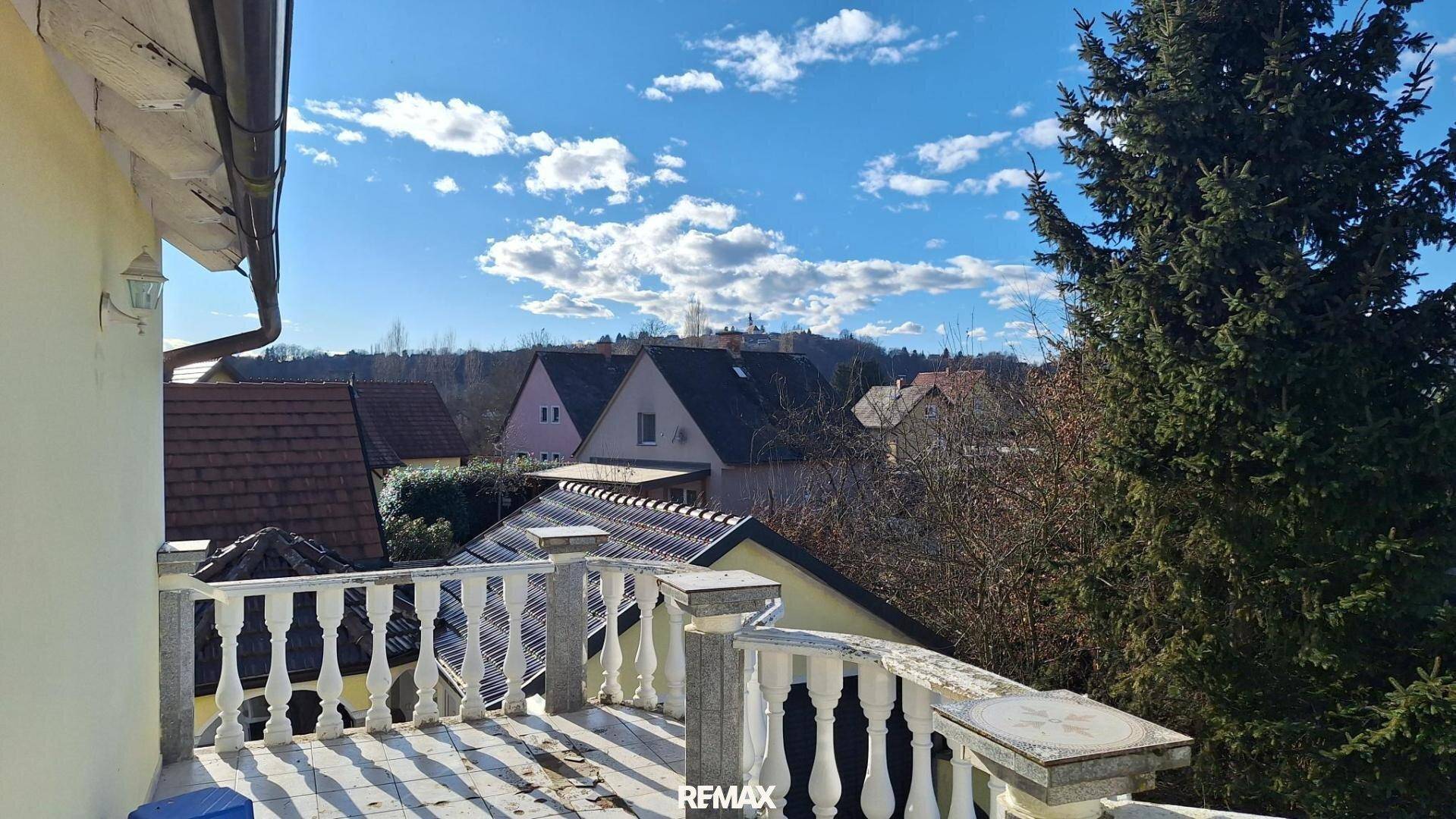 Balkon mit Balustrade und weitem Blick über Dächer und die umliegende Landschaft.