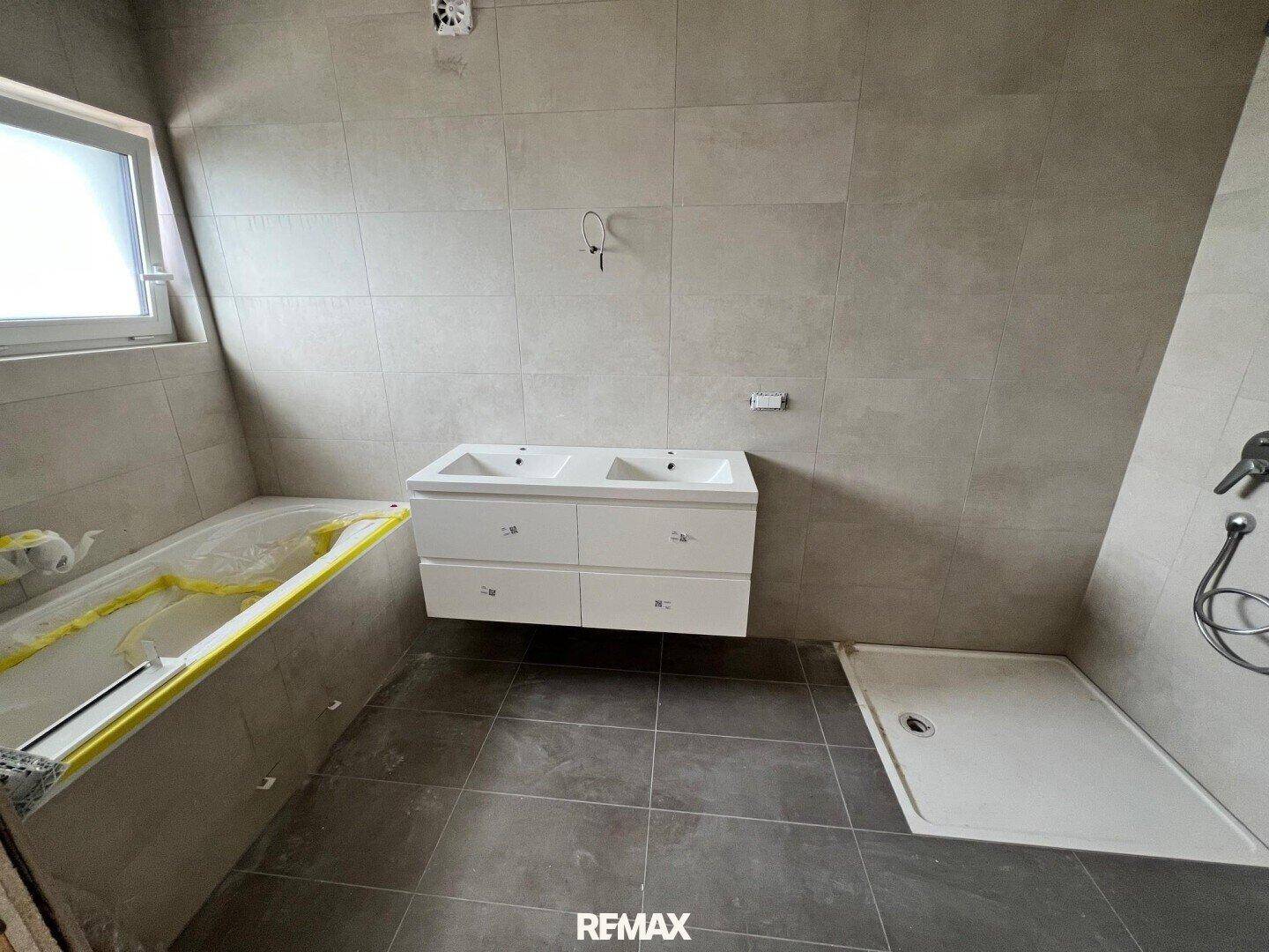 Modernes Badezimmer im Bau mit Doppelwaschbecken, Badewanne und ebenerdiger Dusche.