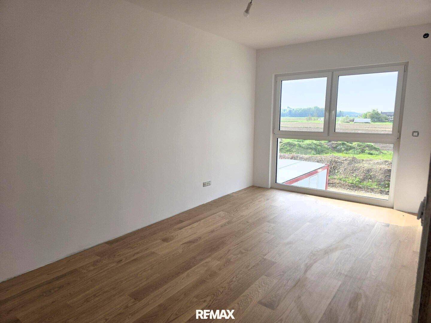 Geräumiges Zimmer mit Parkettboden und weitem Blick auf die umliegende Landschaft.