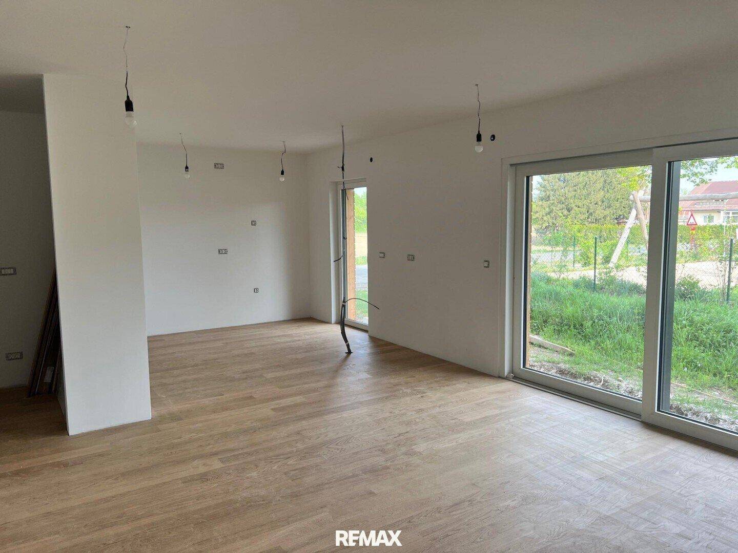 Heller Wohnbereich mit großen Schiebetüren zum Garten und neu verlegtem Parkettboden.