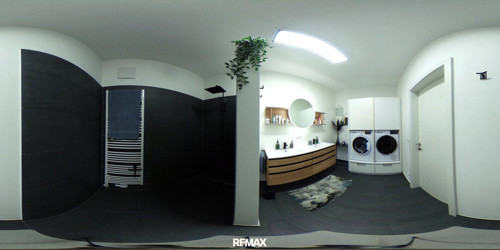 Modernes Badezimmer mit Doppelwaschbecken, Dusche und integriertem Wäschebereich.