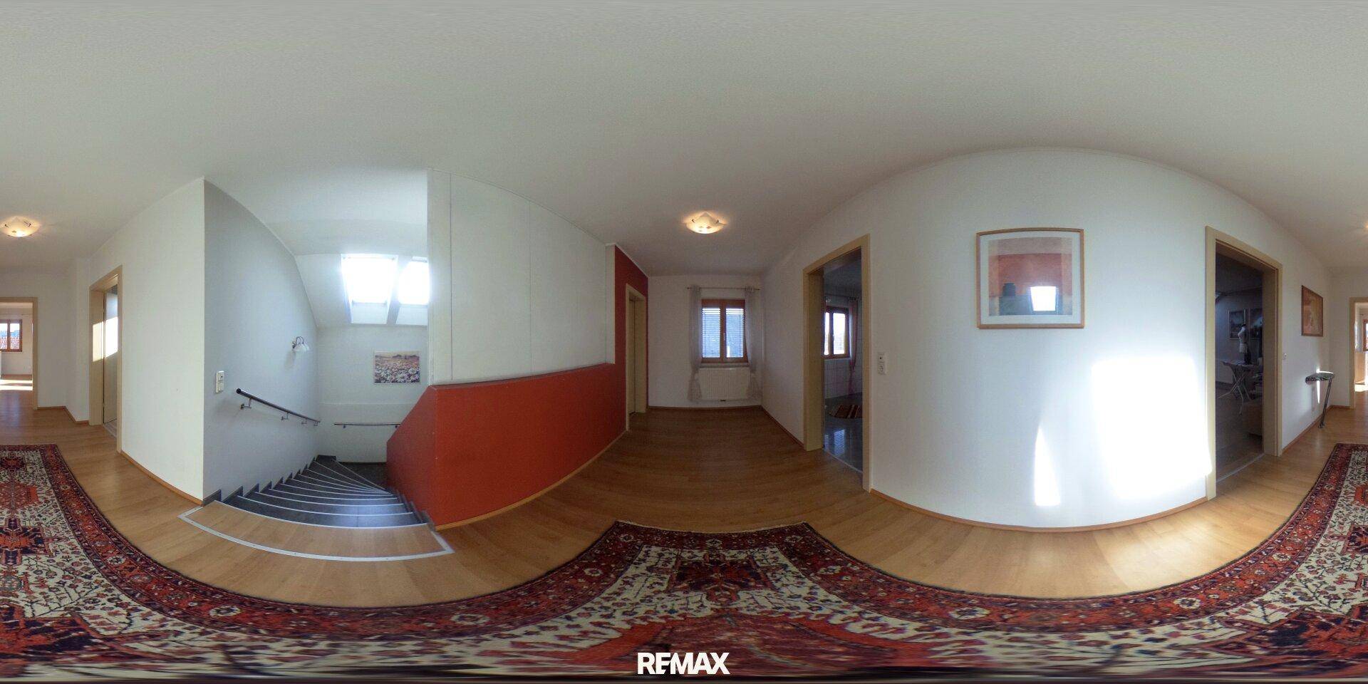 Heller Flur mit Teppichboden, Treppe und Zugang zu weiteren Räumen im Haus.