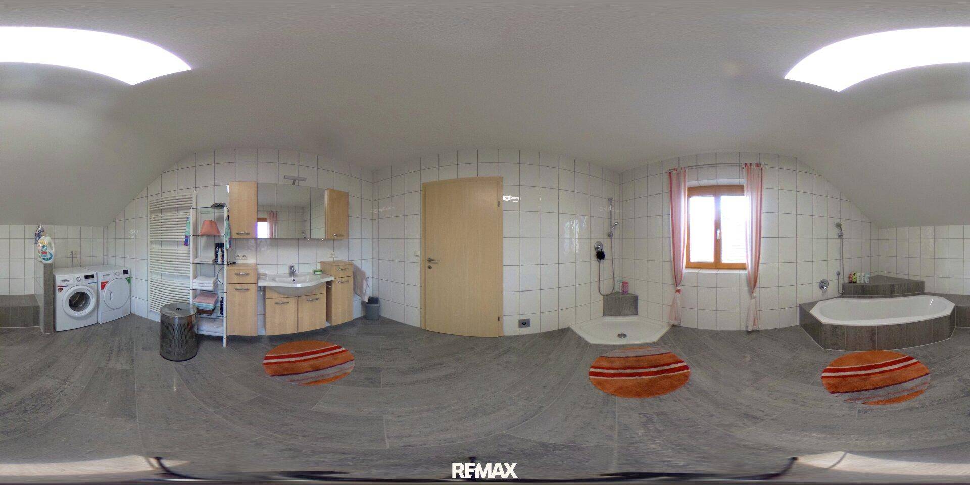 Geräumiges Badezimmer mit Badewanne, Dusche, Waschmaschine und Dachschrägenfenstern.