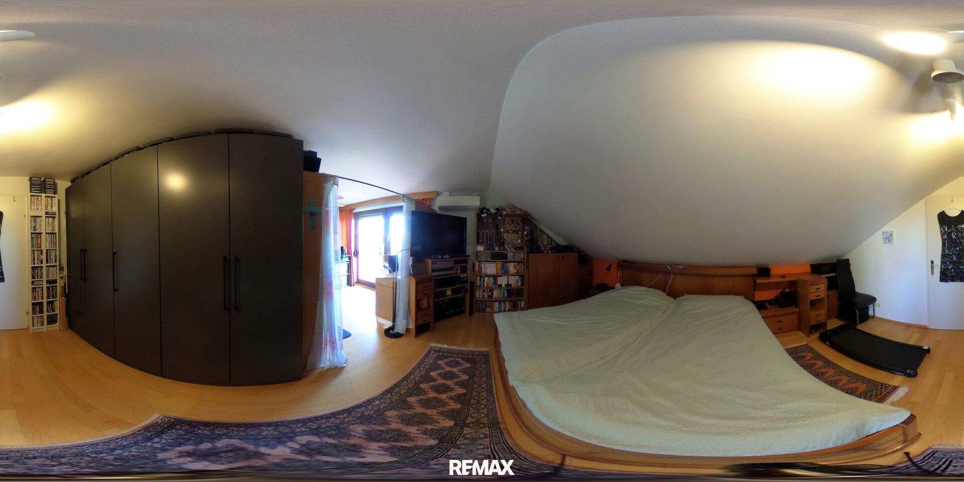 Schlafzimmer mit großem Bett, Holzboden und Dachschräge.