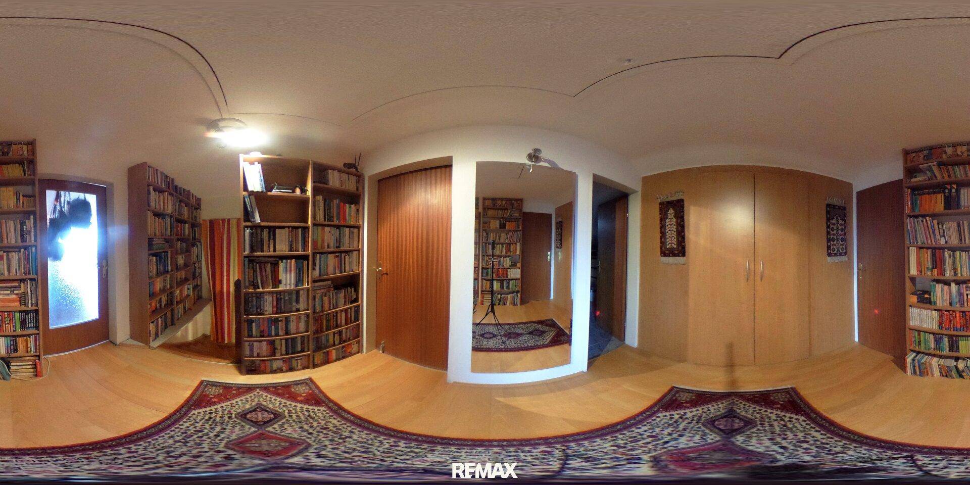 Bibliothek mit umfangreichen Bücherregalen, Holzboden und gemütlicher Atmosphäre.