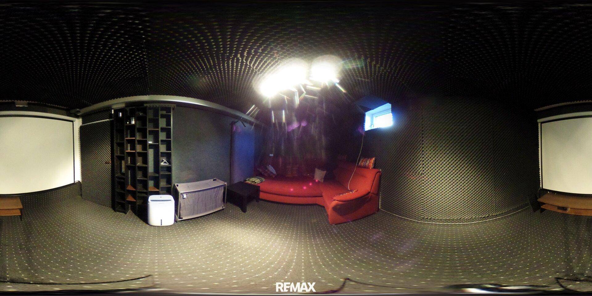 Heimkino mit Projektionsflächen, rotem Sofa und dunkler Wandverkleidung.