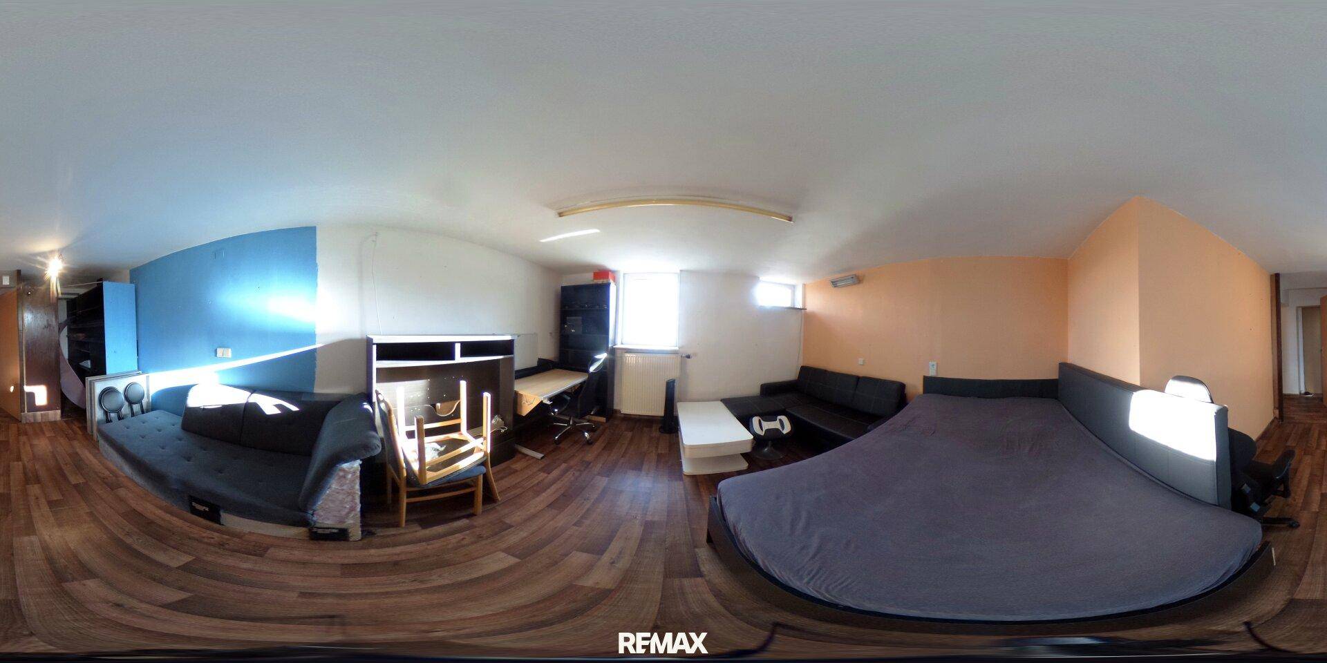 Schlafzimmer mit Bett, Schreibtisch und blauer Akzentwand.