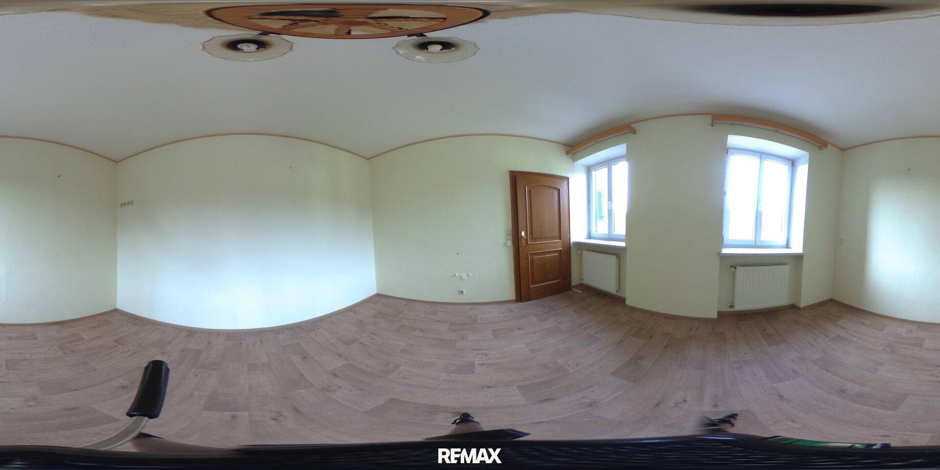 Heller Wohnraum mit Laminatboden, zwei Fenstern und Holztür, bietet vielseitige Nutzungsmöglichkeiten.