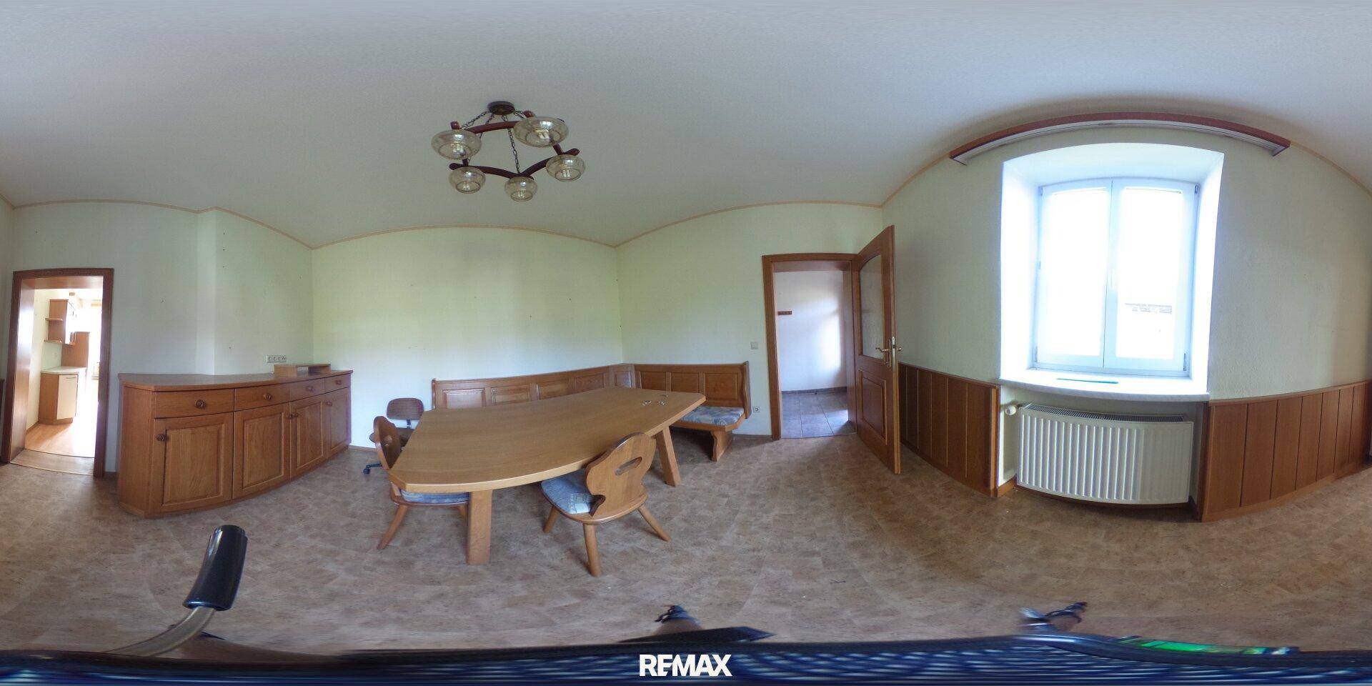 Gemütlicher Essbereich mit Holztisch, Sitzbänken und traditionellen Möbeln, hell durch das Fenster.