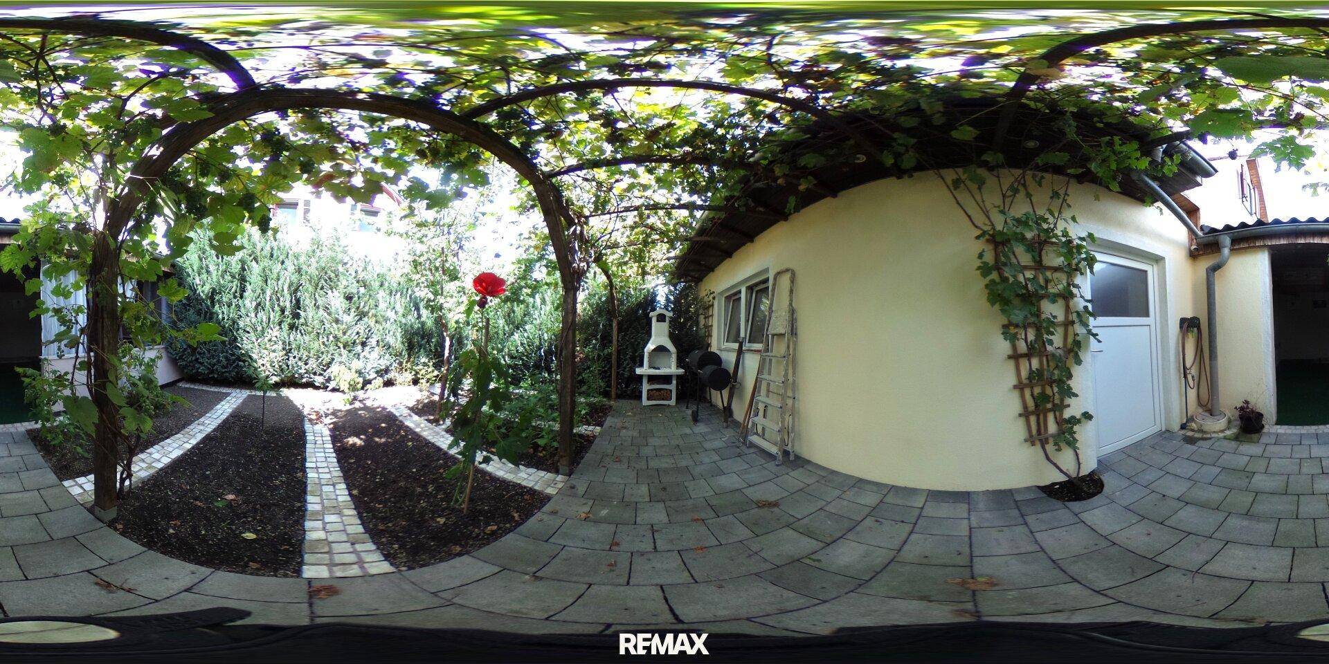 Gepflegter Garten mit Grillplatz, Weinreben und Steinplattenweg für gesellige Stunden.