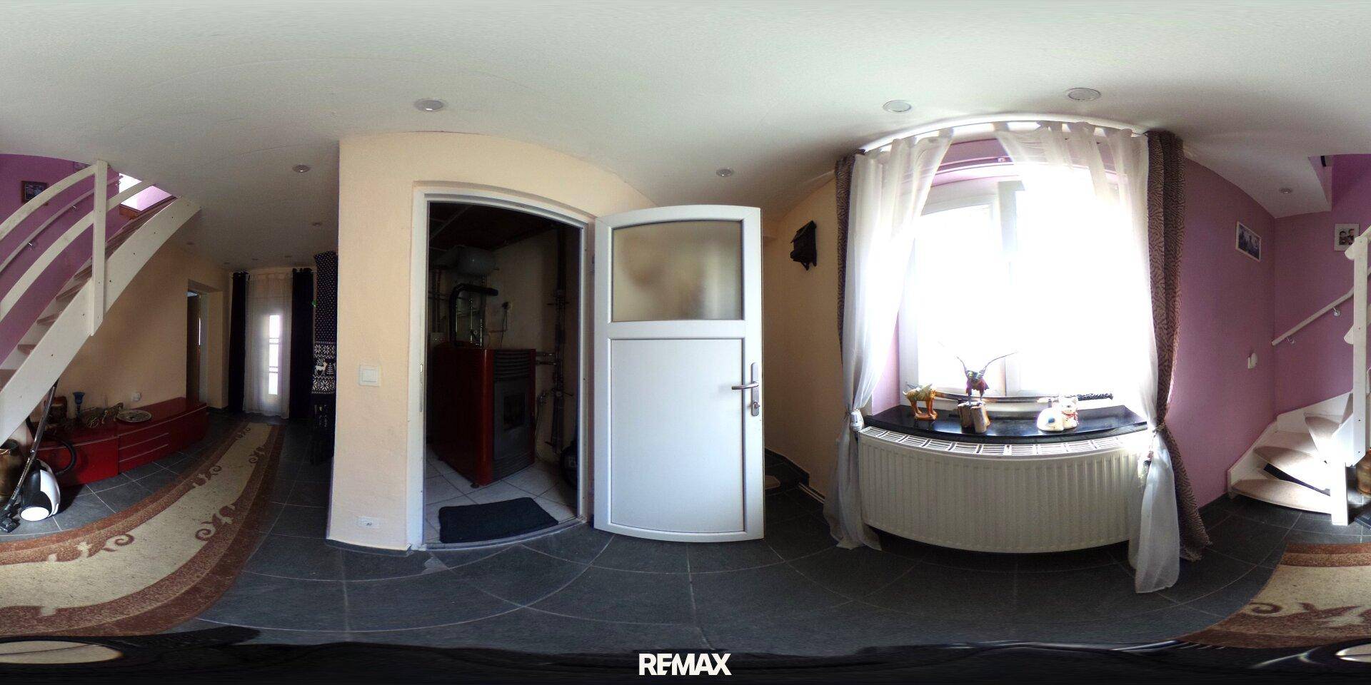 Eingangsbereich mit Treppe, Fenster und Fliesenboden, der zu den oberen Etagen führt.