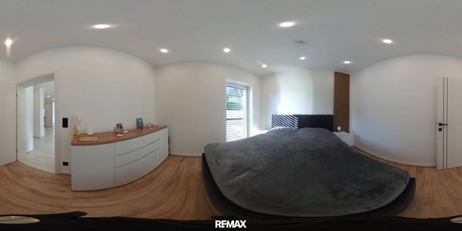 Helles Schlafzimmer mit Holzboden, modernem Bett und weißem Sideboard, gut beleuchtet.