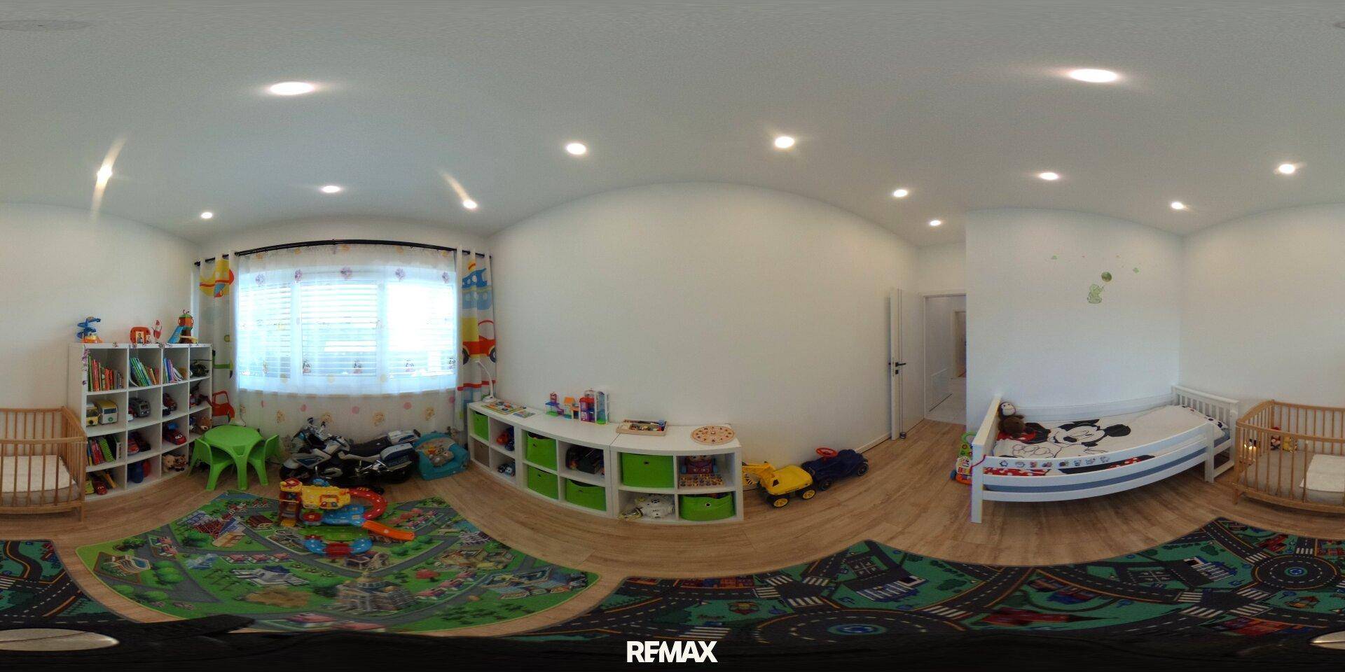Helles Kinderzimmer mit Spielbereich, Holzboden und bunten Teppichen, ideal zum Spielen.