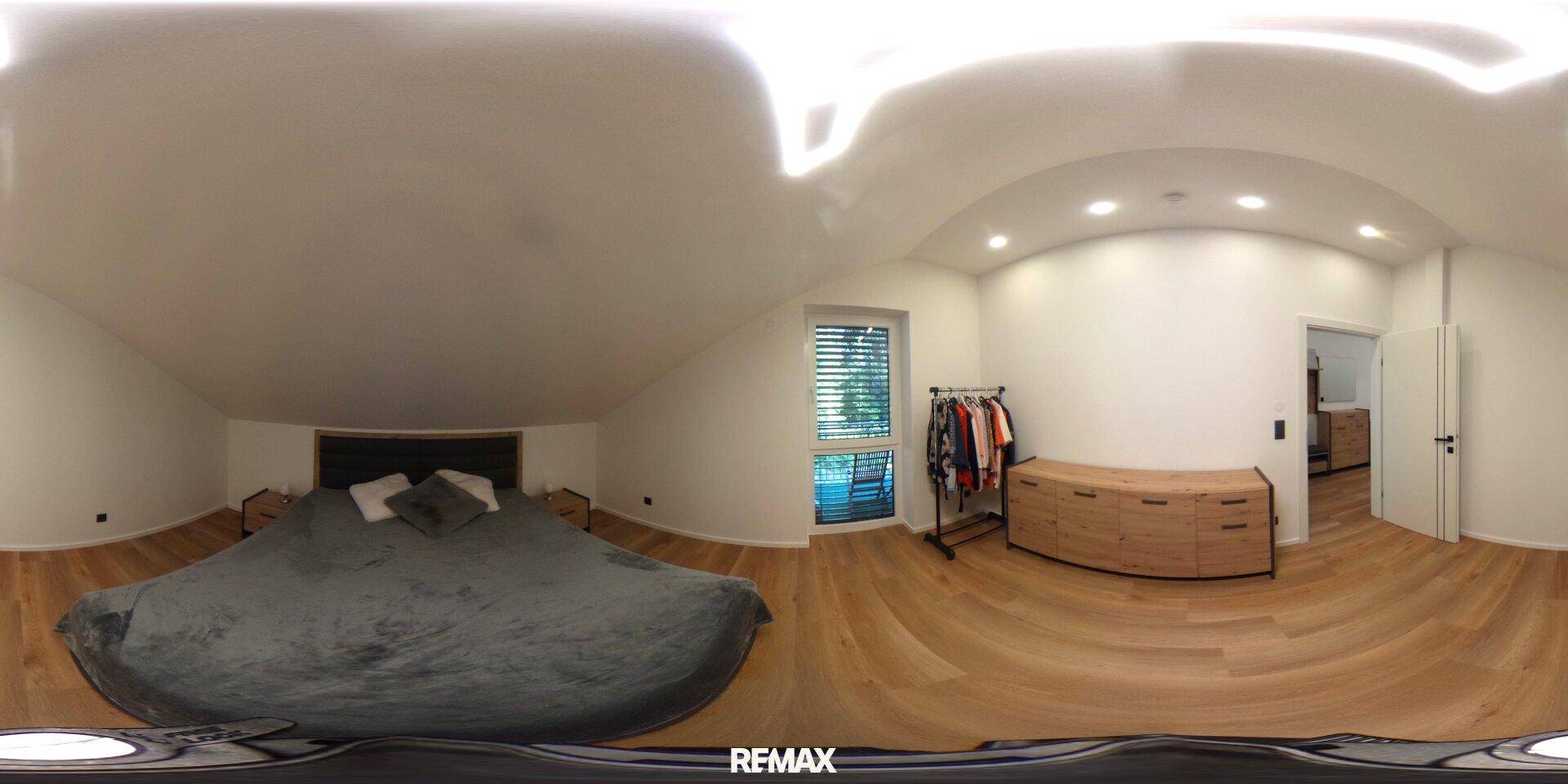 Gemütliches Schlafzimmer mit Holzboden, großem Bett und Kleiderständer, hell durch ein Fenster.