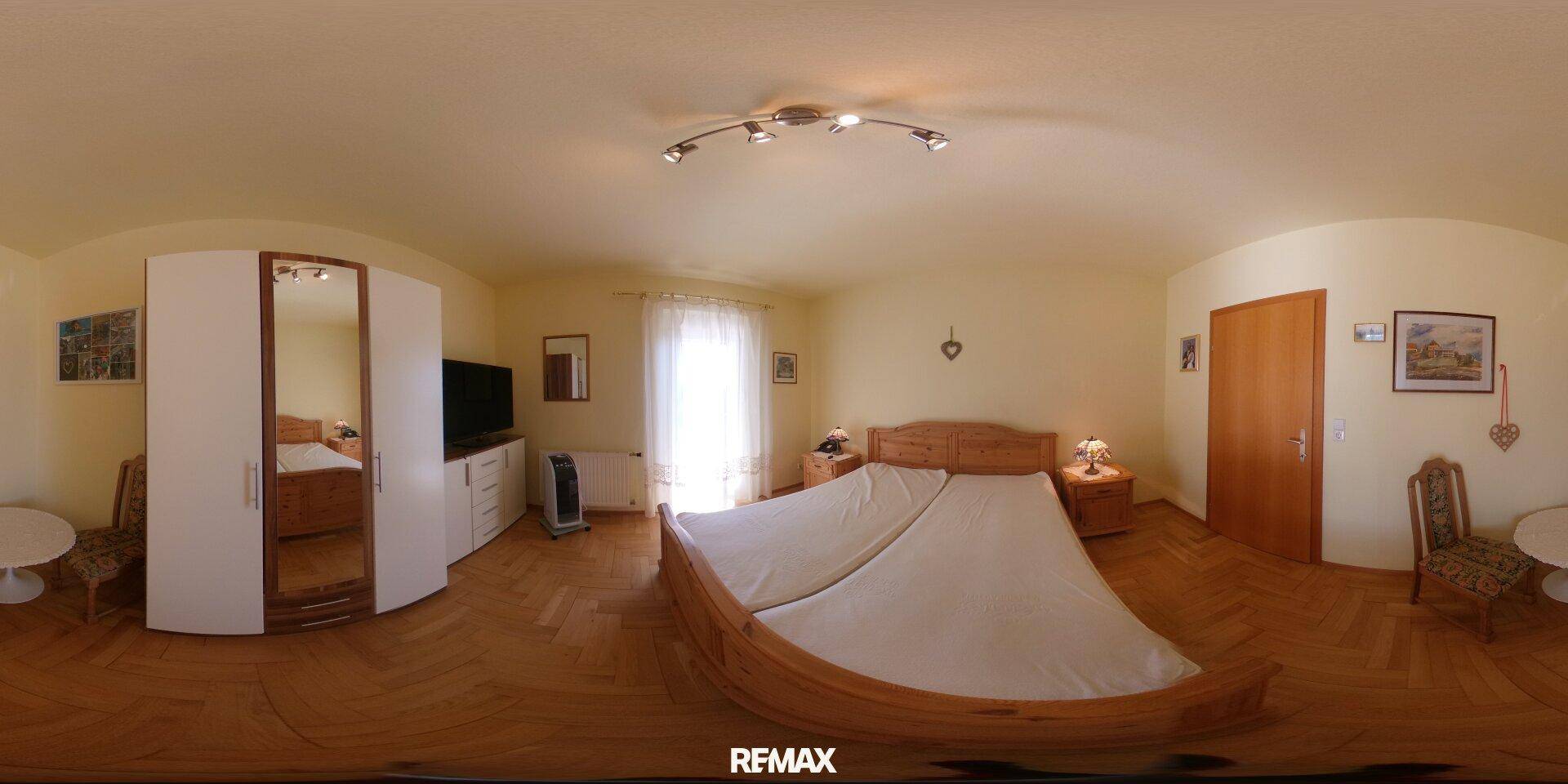 Helles Schlafzimmer mit großem Bett, Holzboden und Fenster, das für eine angenehme Atmosphäre sorgt.