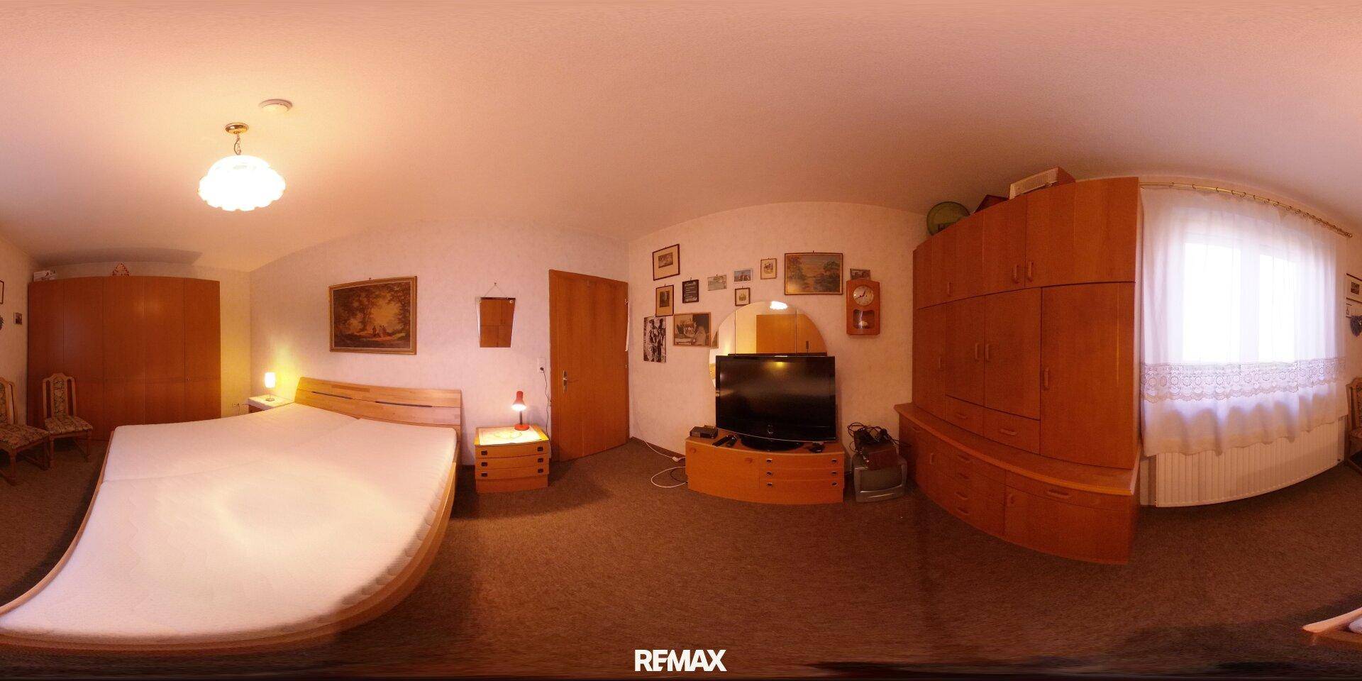 Geräumiges Schlafzimmer mit großem Bett, Holzschrank und Teppichboden, gut beleuchtet.
