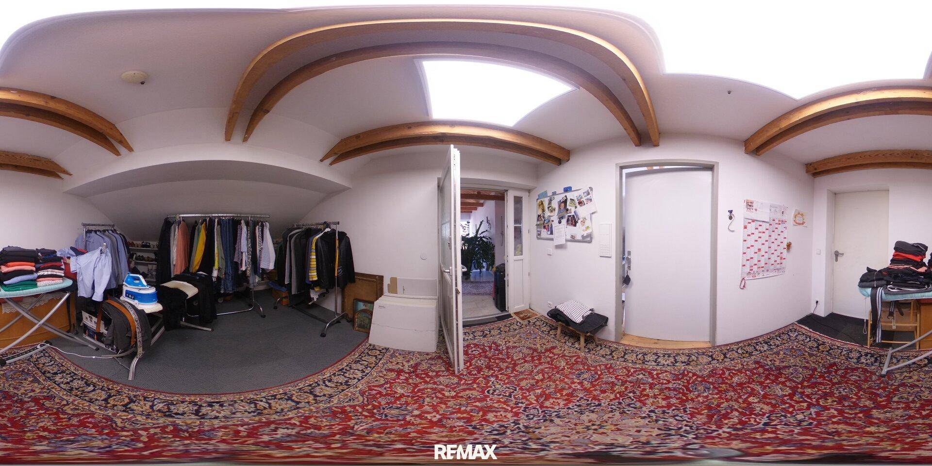 Raum mit Kleiderständern, Teppichboden und gewölbter Decke mit Dachfenster, ideal als Ankleidezimmer.