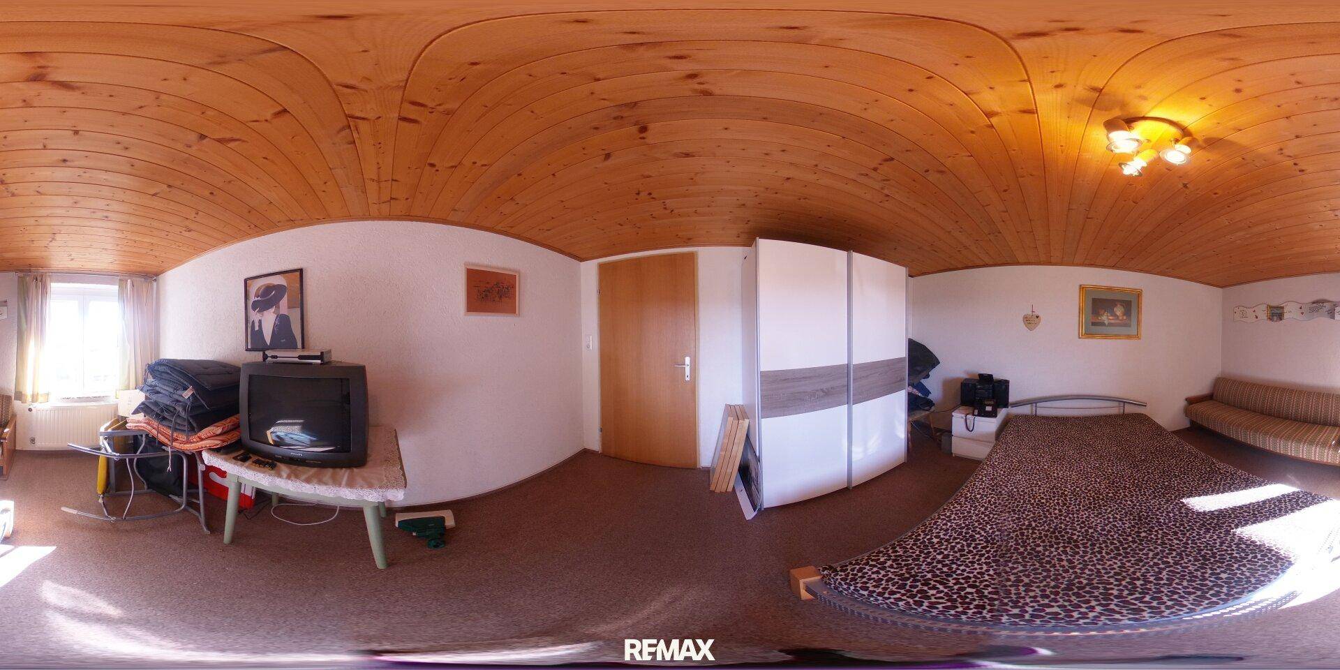 Gemütliches Schlafzimmer mit Holzbalkendecke, Teppichboden und Kleiderschrank, hell durch das Fenster.