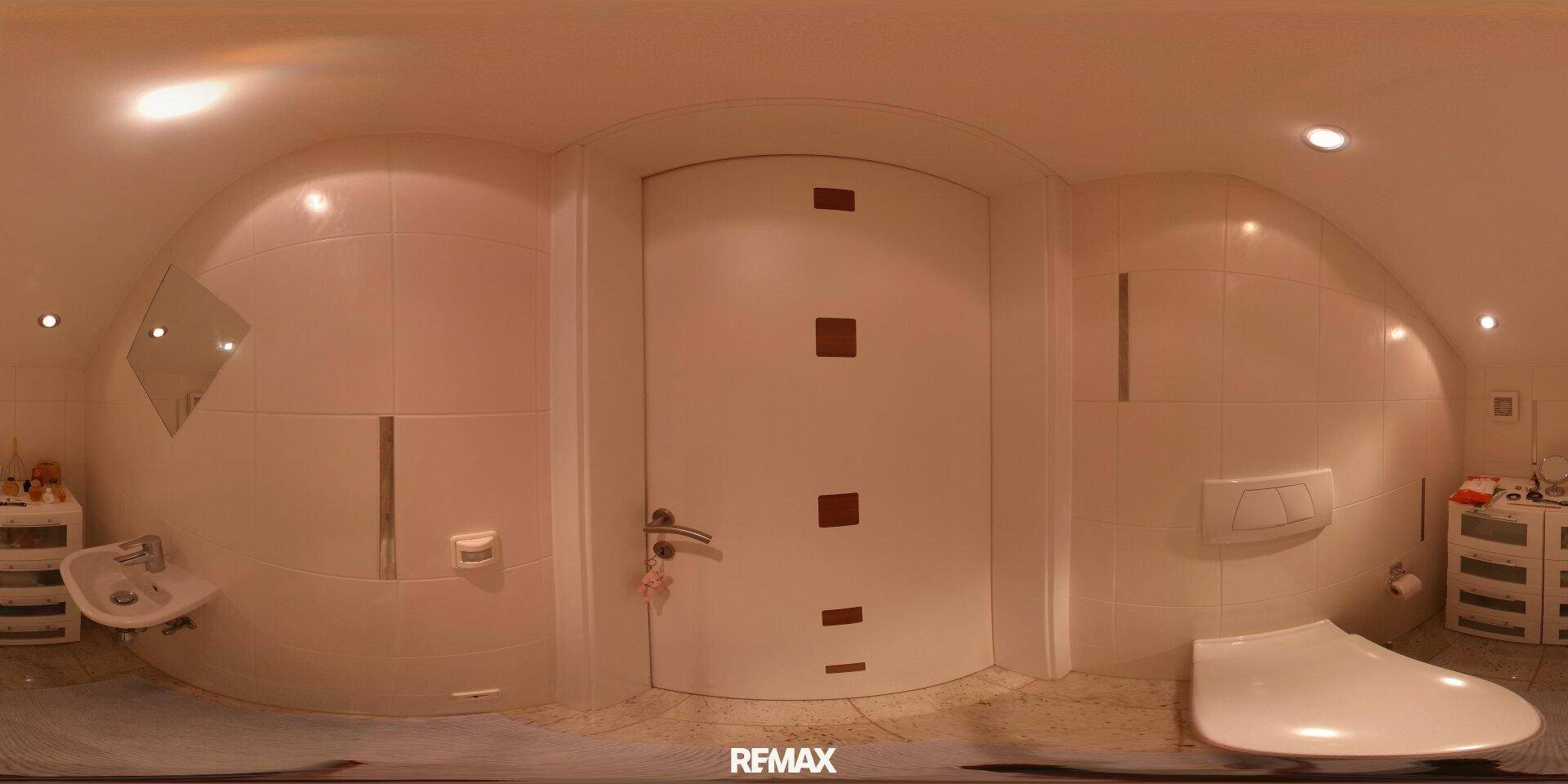 Kleines Badezimmer mit Wand-WC und Waschbecken, komplett gefliest und funktional.