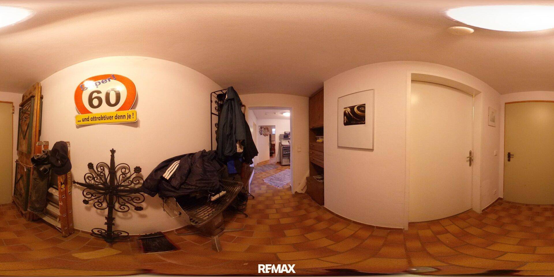 Eingangsbereich mit Fliesenboden, Garderobe und dekorativen Elementen, gut beleuchtet.