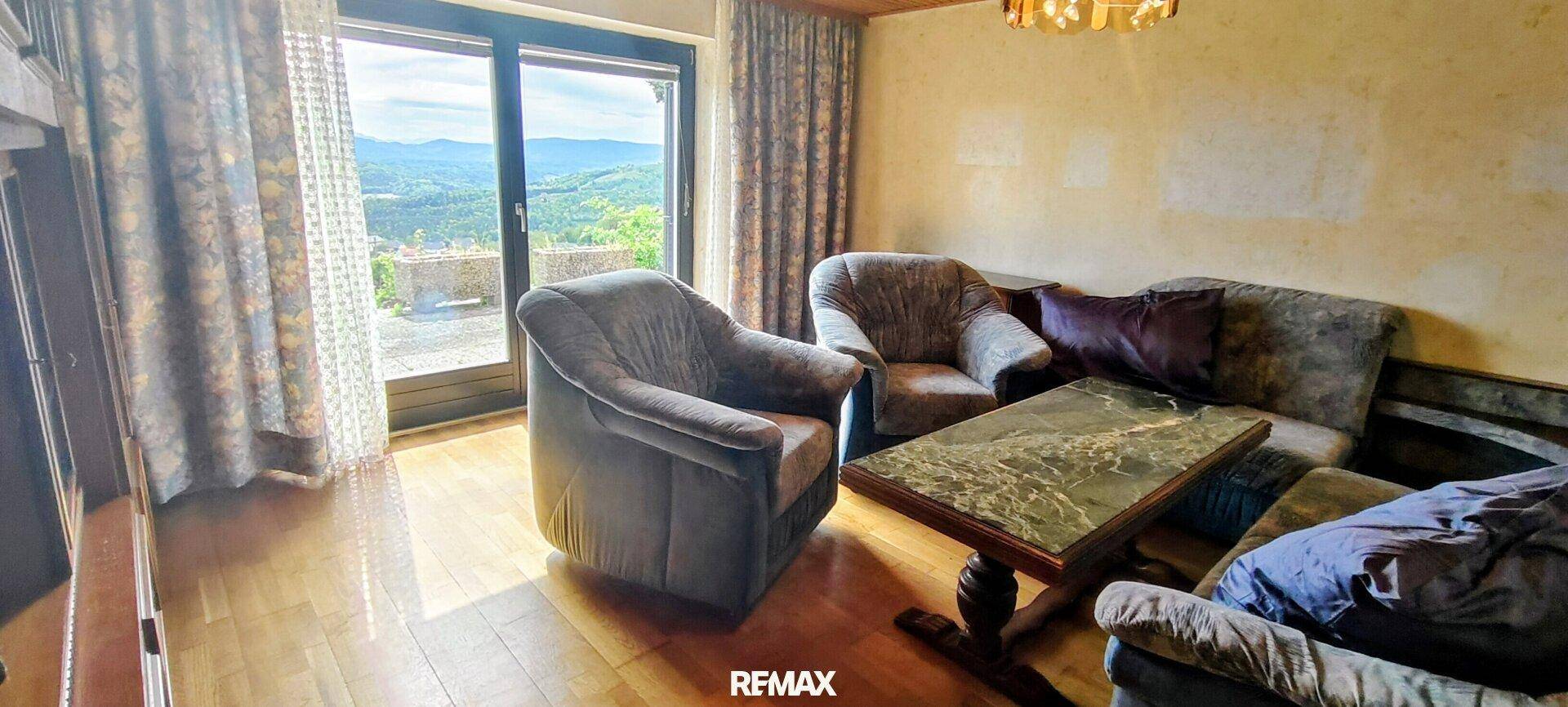 Gemütliches Wohnzimmer mit traditionellen Möbeln, Parkettboden und Panoramablick auf die Landschaft.