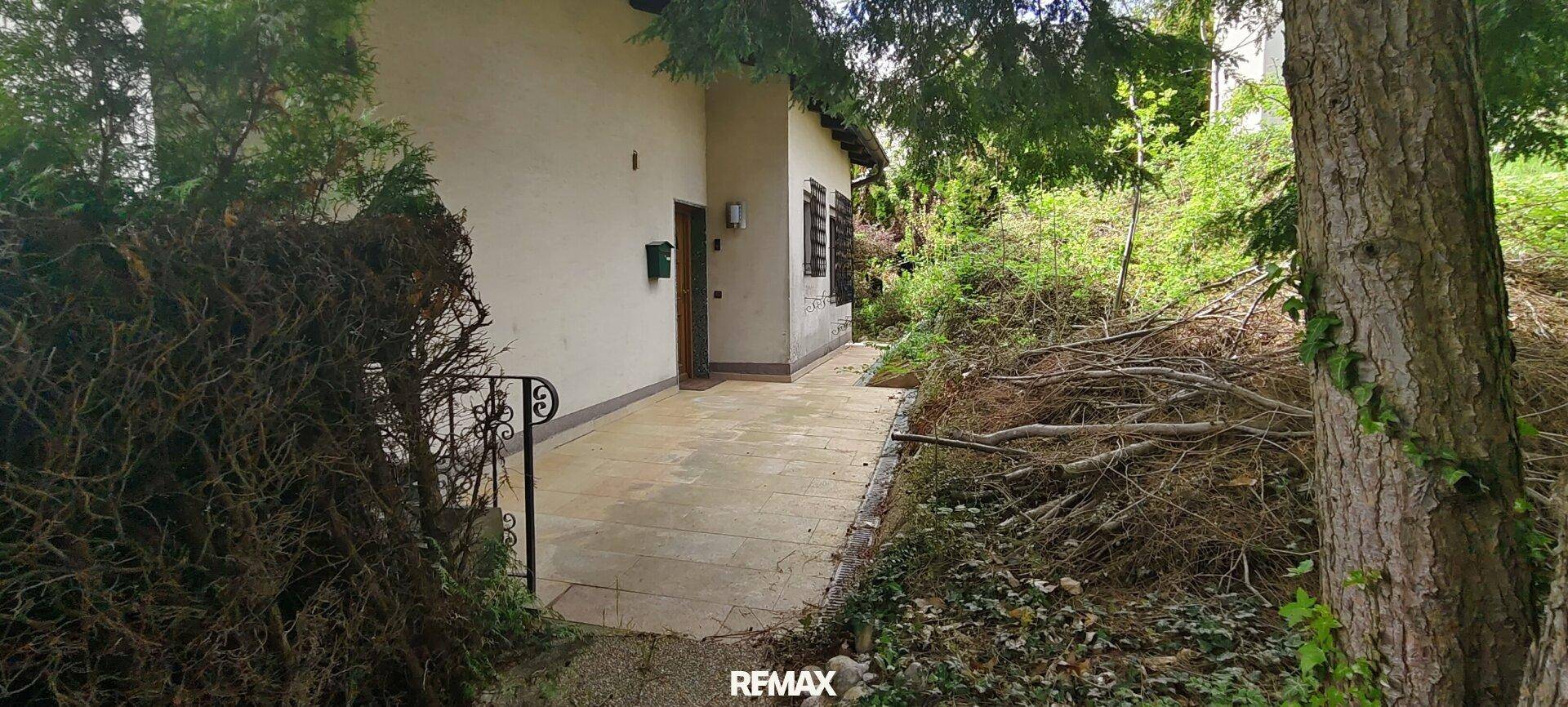 Seitenansicht des Hauses mit Zugang zu einem naturbelassenen Gartenbereich.