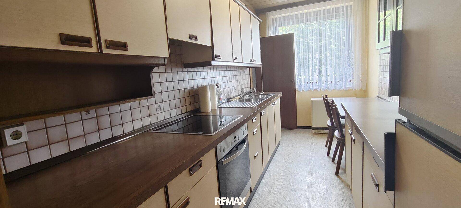 Funktionale Küche mit Einbauschränken, Fliesenrückwand und Essbereich am Fenster.