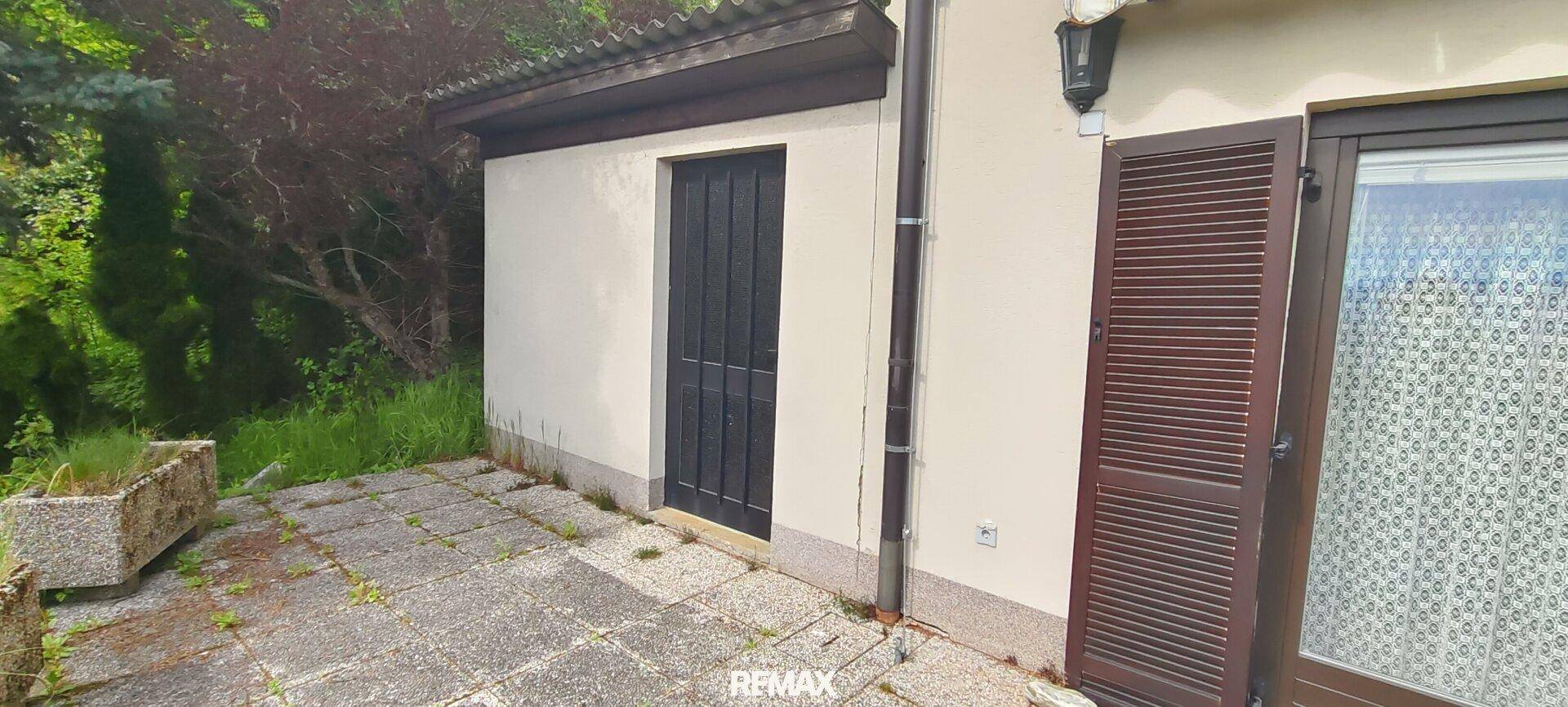 Kleine gepflasterte Terrasse neben dem Haus, ideal für einen ruhigen Sitzbereich im Freien.
