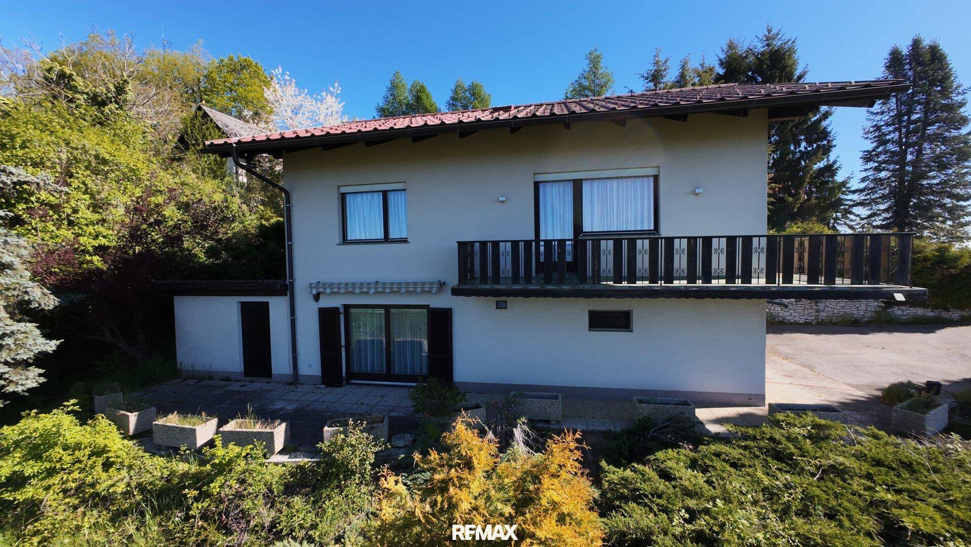 Vorderansicht des Hauses mit Balkon, Terrasse und gepflegtem Gartenbereich.