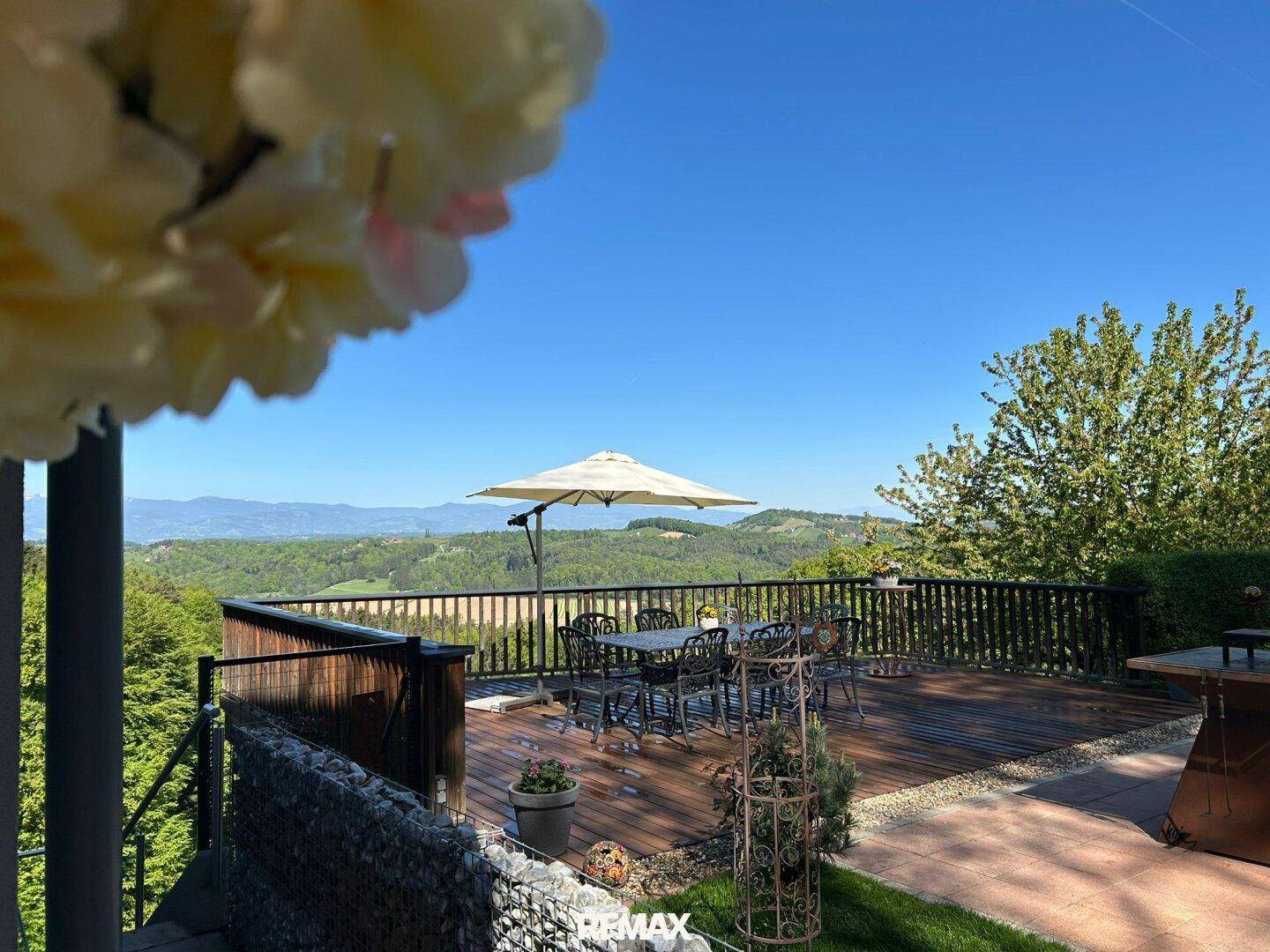 Sonniger Terrassenbereich mit Gartenmöbeln und weitem Blick über die Landschaft.