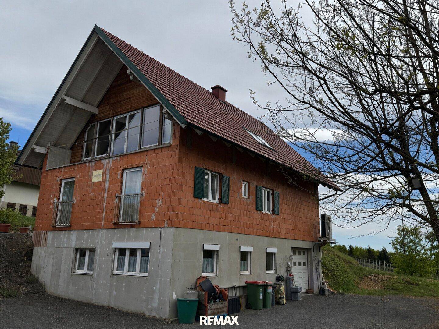 Rückansicht des Hauses mit Ziegelmauerwerk, Satteldach und einem Untergeschoss mit Garagenzugang.