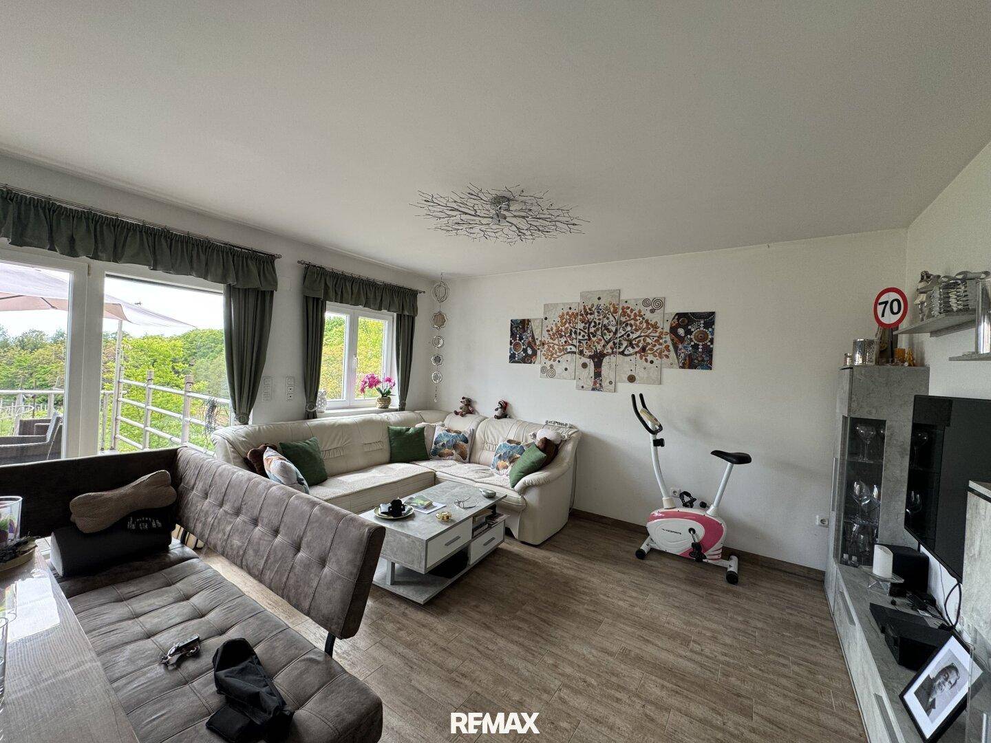 Helles Wohnzimmer mit Laminatboden, Ecksofa und Zugang zu einem Balkon mit schöner Aussicht.