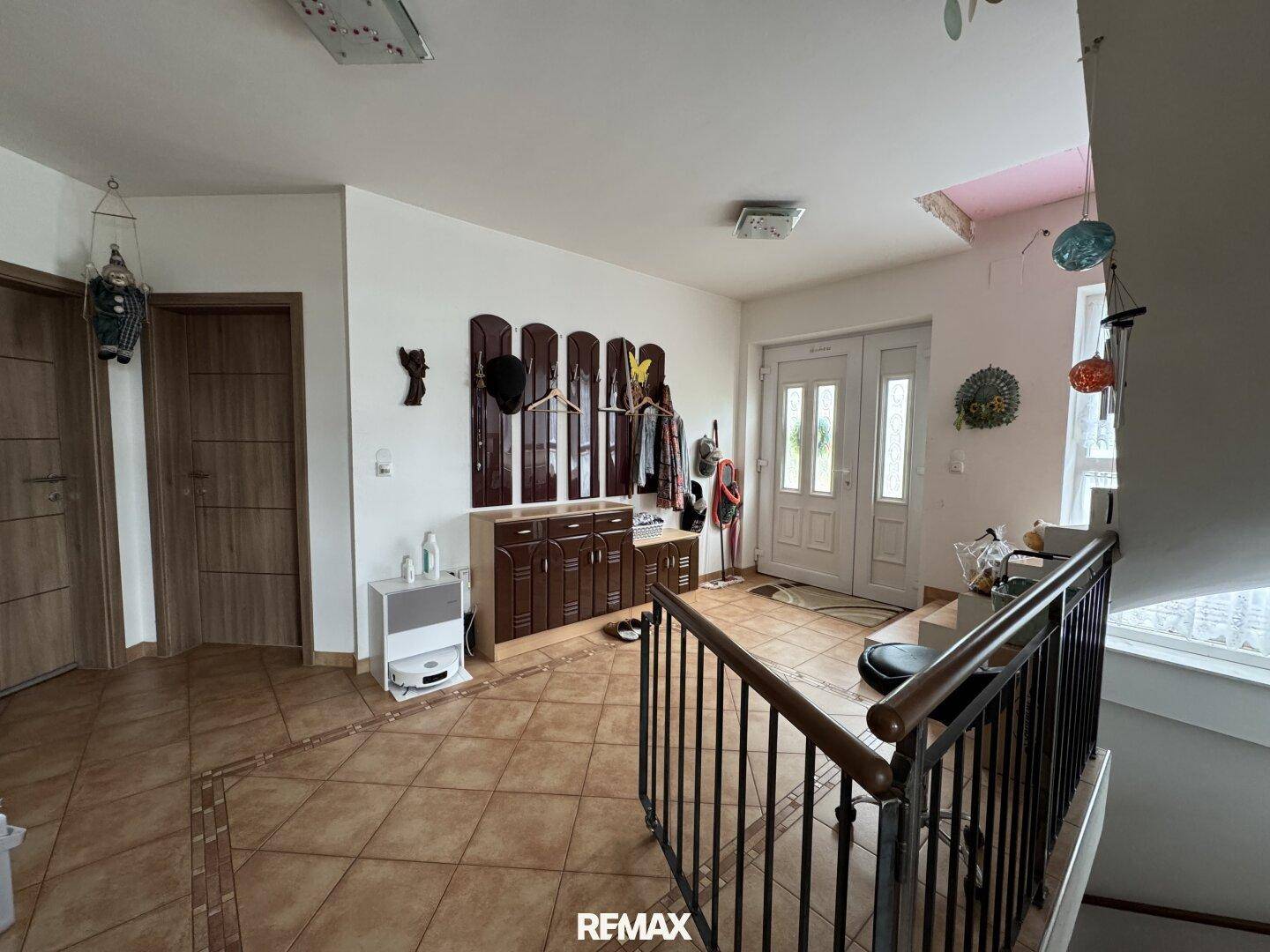 Geräumiger Eingangsbereich mit Fliesenboden, Garderobe und Zugang zu verschiedenen Räumen.