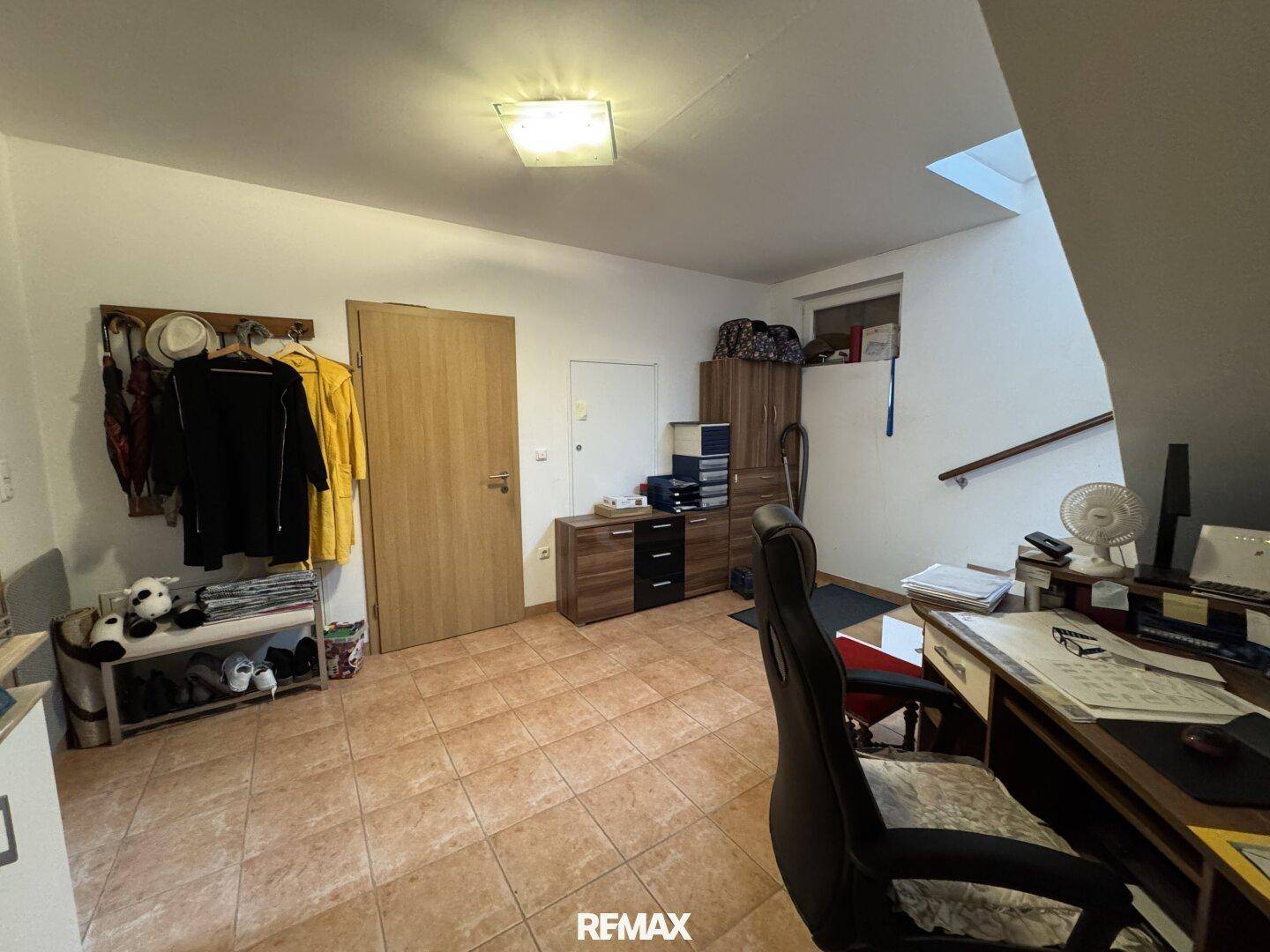 Geräumiger Kellerflur mit Fliesenboden, Garderobe und Zugang zu weiteren Kellerräumen.