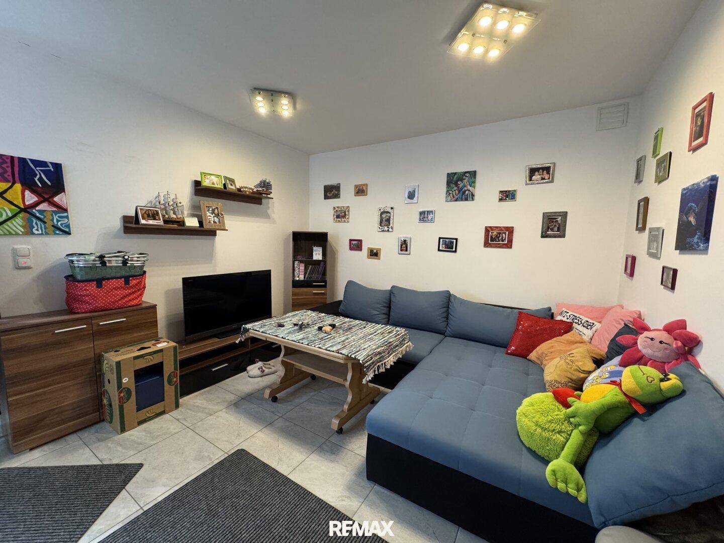 Gemütlicher Wohnbereich im Keller mit Sofa, Fernseher und vielen persönlichen Dekorationen.