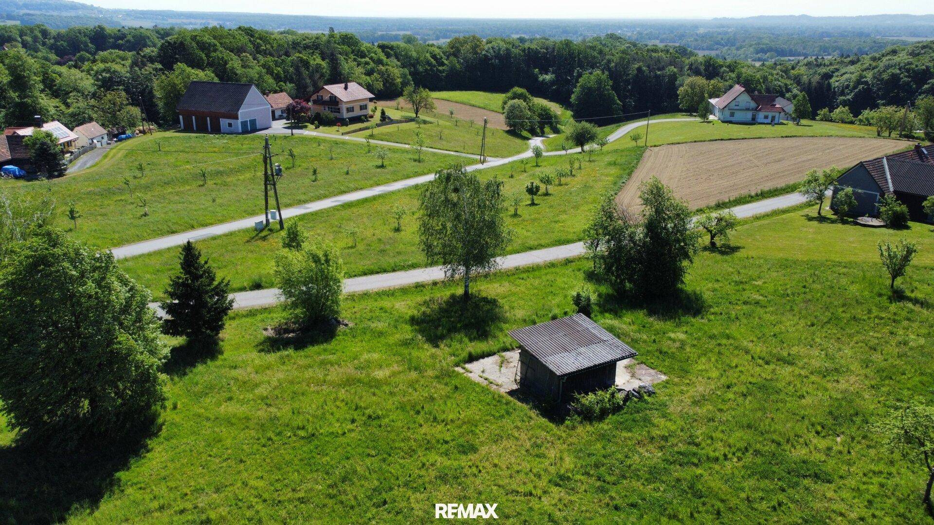 Ländliche Gegend mit Häusern, Straßen, einer kleinen Hütte und weiter Landschaft unter klarem Himmel.