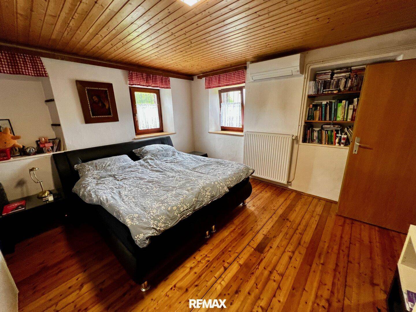 Schlafzimmer mit Holzboden, Holzdecke und einem Doppelbett, hell und gemütlich.