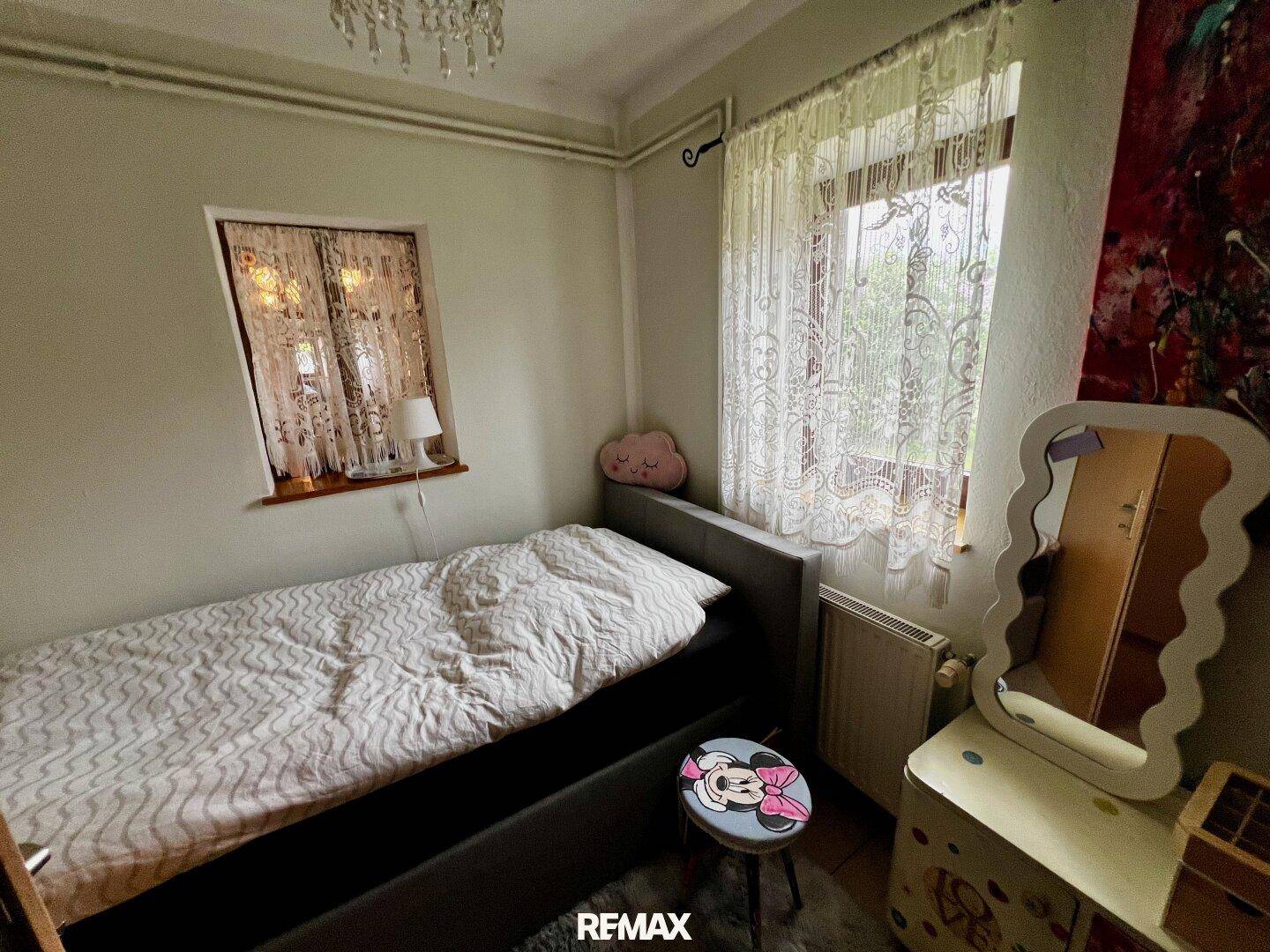 Kinderzimmer mit Einzelbett, Teppichboden und verspielter Dekoration, hell und freundlich.