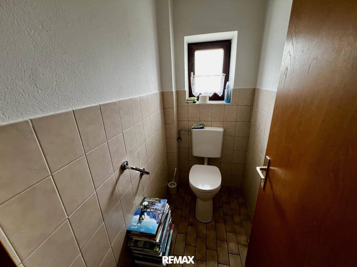 Separate Toilette mit Fliesenboden und Fenster, einfach und sauber.